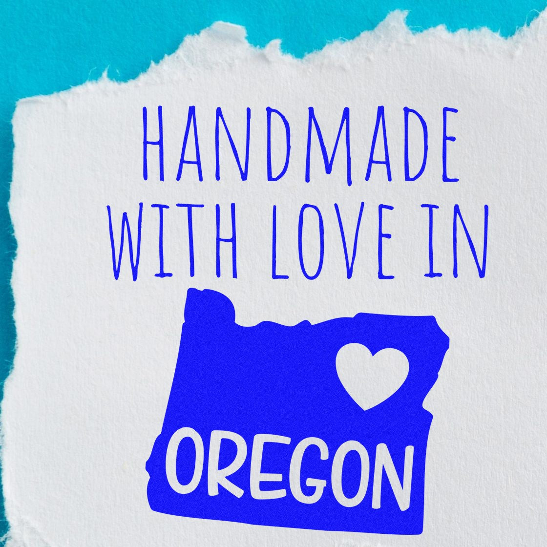 Self-Inking Oregon Handmade with Love Stamp featuring a blue map of Oregon with a heart, and the text Handmade with Love in Oregon on a torn paper background. Perfect for crafts and gifts.