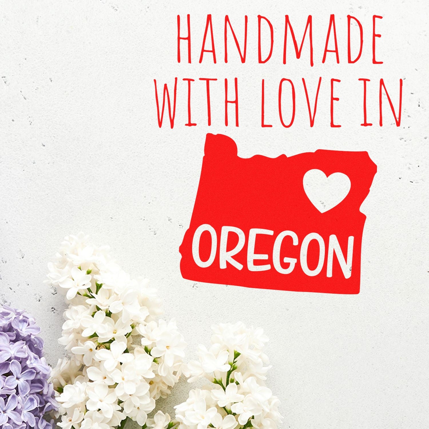 Handmade with Love in Oregon Slim Pre-Inked Stamp featuring a red Oregon state outline with a heart, surrounded by white and purple flowers. Perfect for crafts and personalizing gifts.