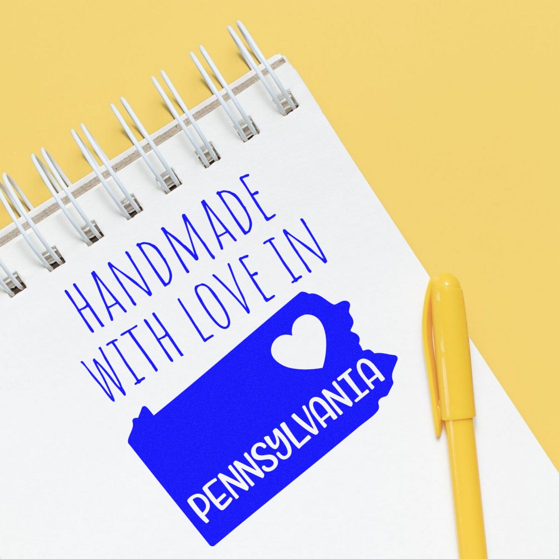 Wood Handle Pennsylvania Handmade with Love Rubber Stamp on a notepad, featuring a blue Pennsylvania state outline with a heart, and text Handmade with Love in Pennsylvania in bold letters.