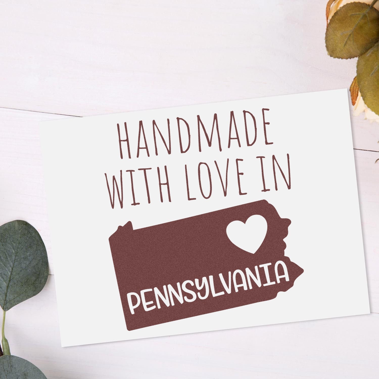 Handmade with Love in Pennsylvania Slim Pre-Inked Stamp featuring a heart and state outline design on a white card, surrounded by green leaves on a light background.