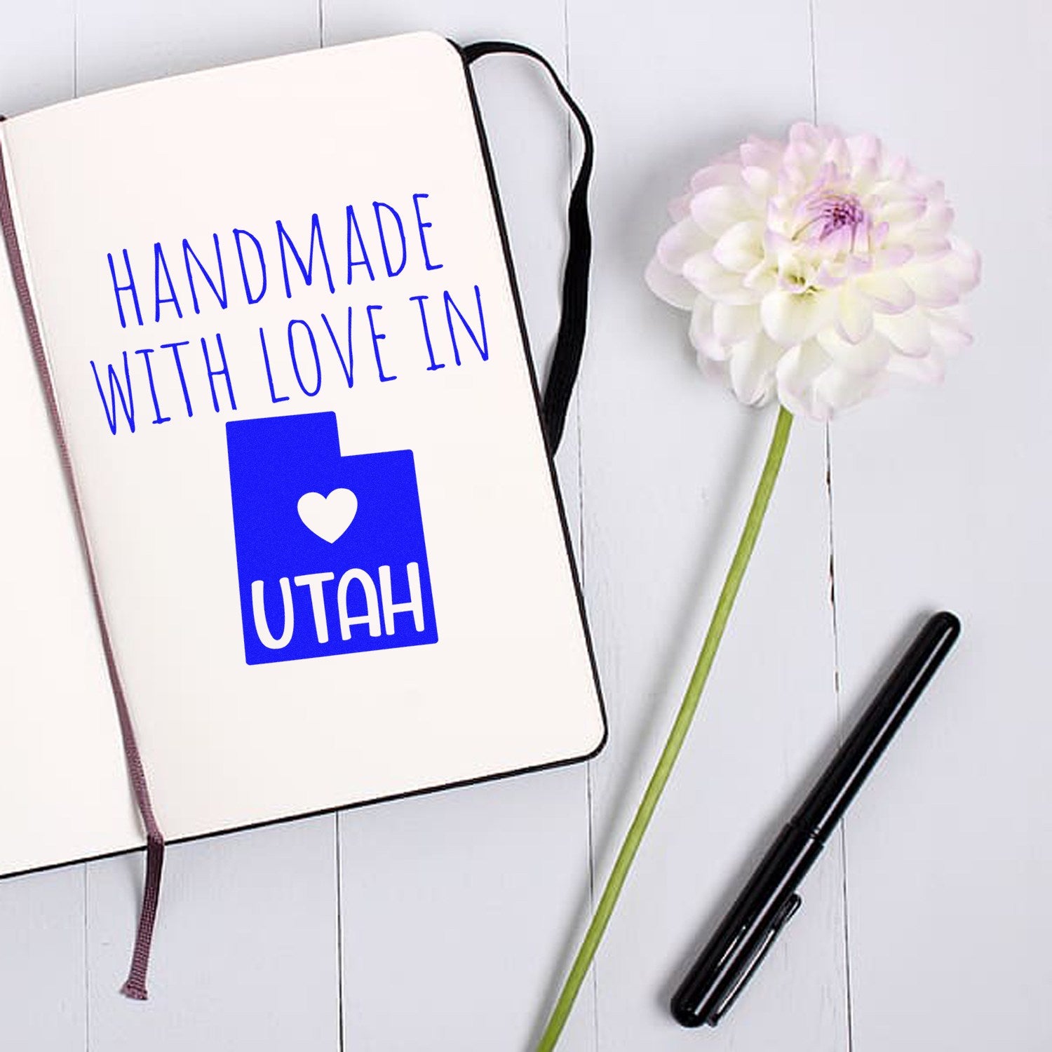 Wood Handle Utah Handmade with Love Rubber Stamp on open notebook with flower, showcasing blue 'Handmade with Love in Utah' design. Perfect for crafts and personalized projects.