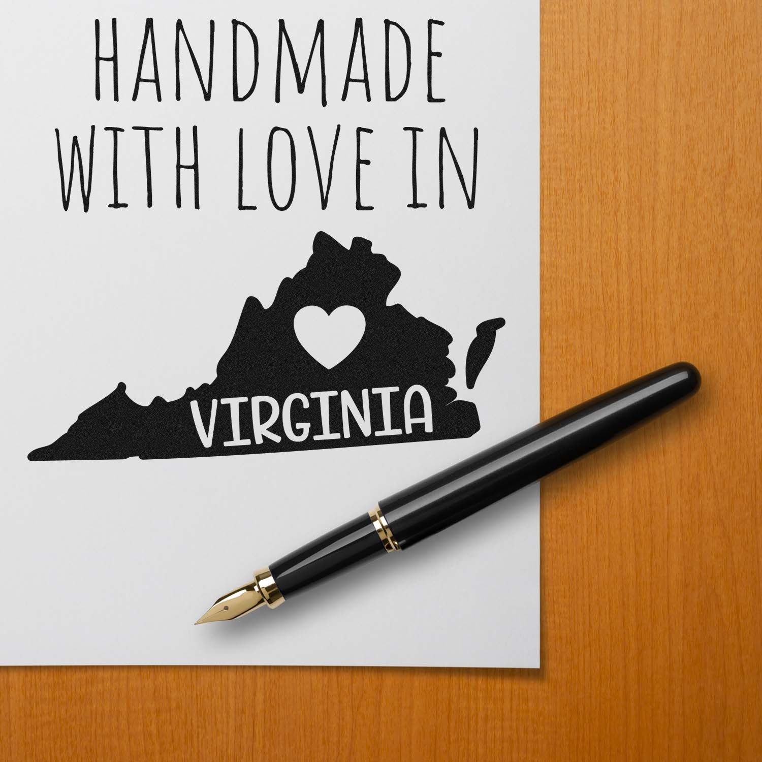 Handmade with Love in Virginia Slim Pre-Inked Stamp on paper with Virginia map and heart, next to a black fountain pen on a wooden surface.