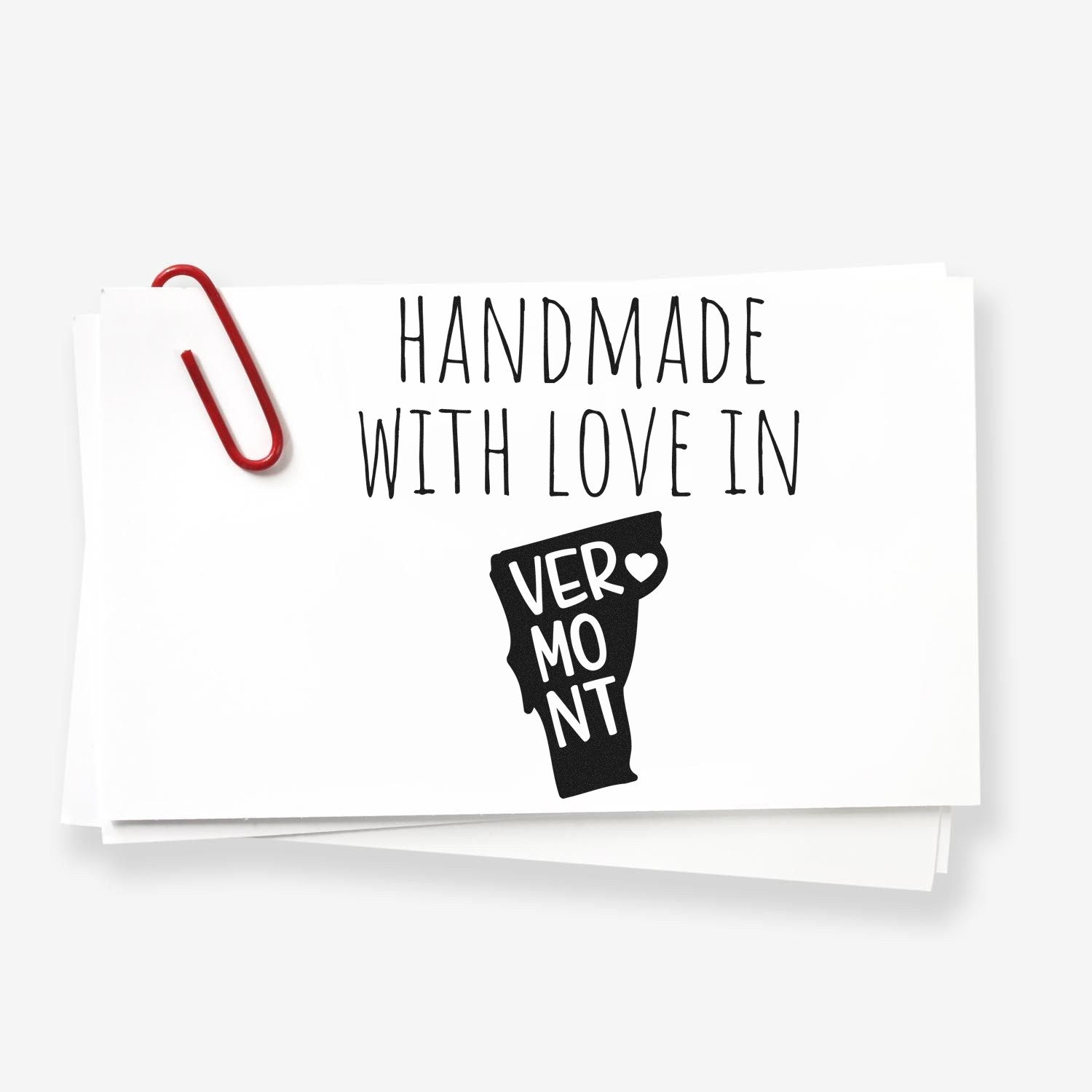 Self-Inking Vermont Handmade with Love Stamp featuring a Vermont silhouette and heart, perfect for crafts and gifts. Includes a red paperclip on white cards.