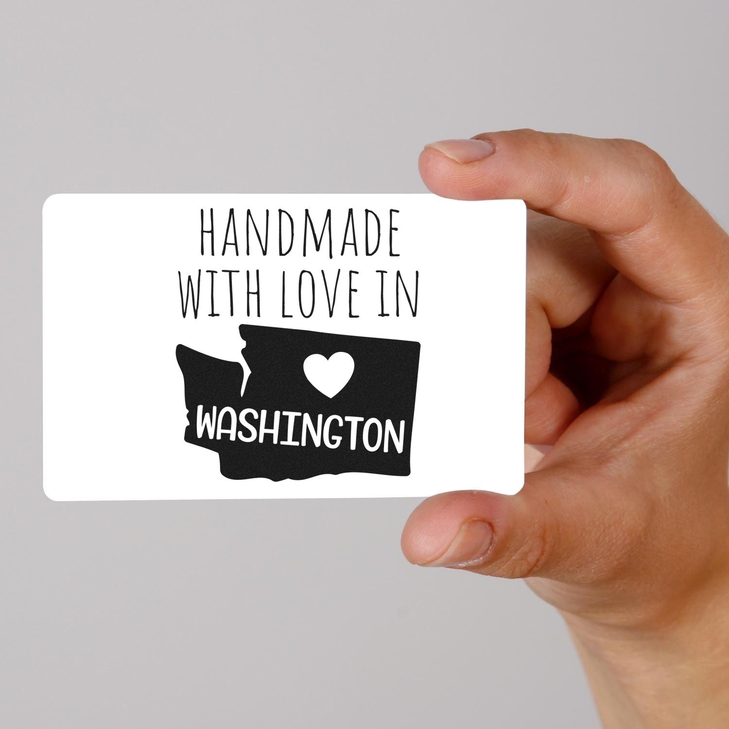 Self-Inking Washington Handmade with Love Stamp featuring a heart and state outline, held in hand. Perfect for crafts and gifts. Black ink on white background.