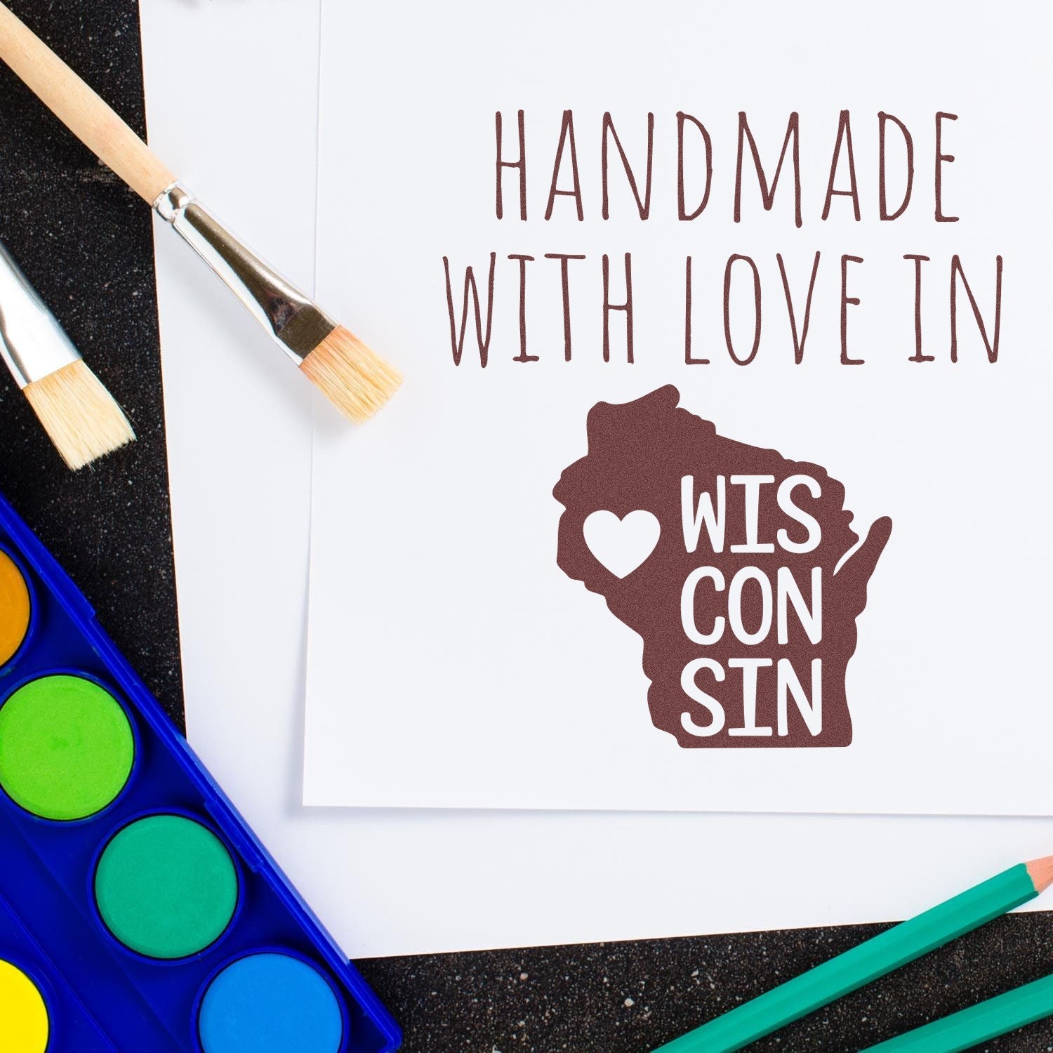 Wood Handle Wisconsin Handmade with Love Rubber Stamp on paper, featuring a heart and state outline, surrounded by paintbrushes and watercolor palette. Perfect for crafts and gifts.