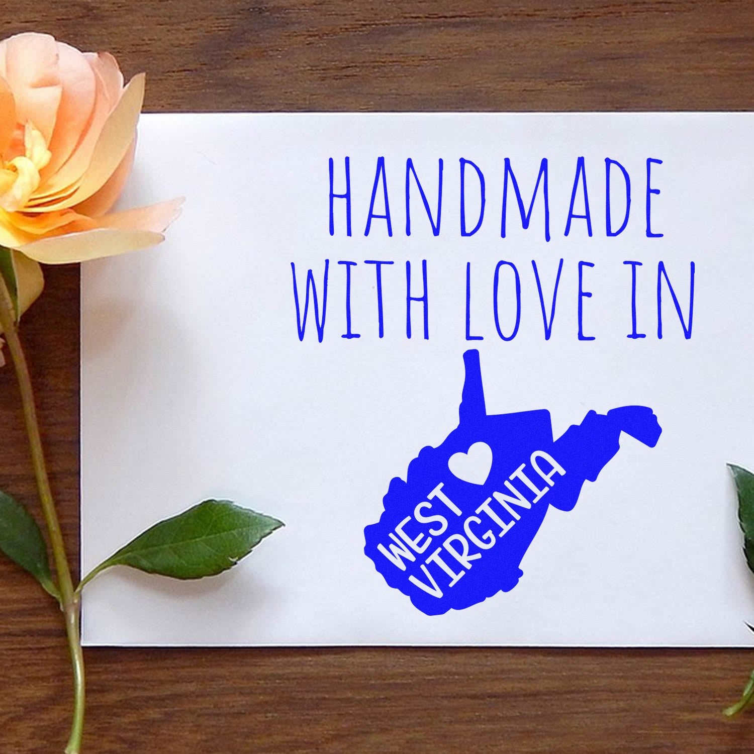 Self-Inking West Virginia Handmade with Love Stamp on white paper, featuring blue text and a heart design. Perfect for adding a personal touch to crafts and gifts.