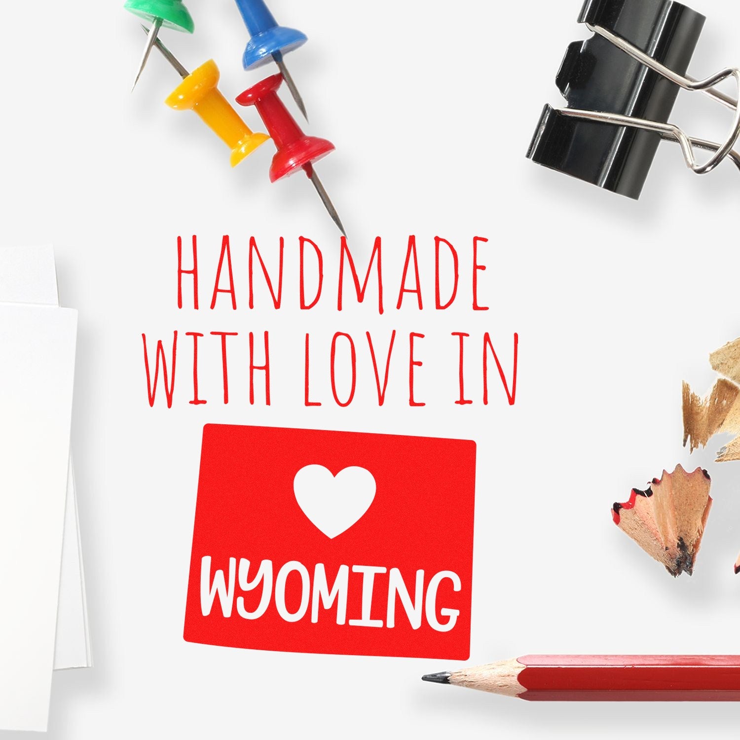 Handmade with Love in Wyoming Slim Pre-Inked Stamp on a desk with colorful push pins, binder clip, pencil, and paper shavings. Perfect for adding a personal touch to your stationery.