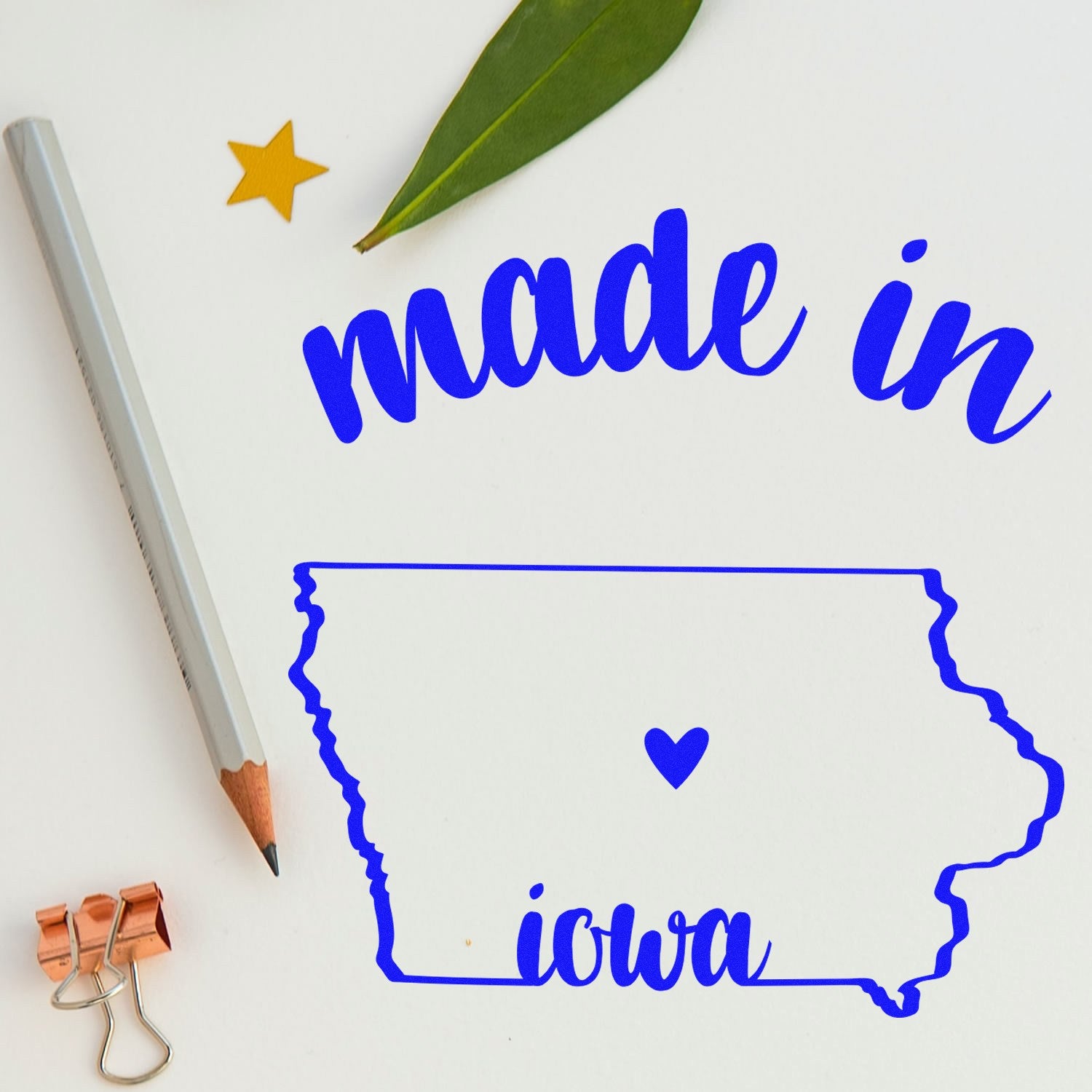 Slim Pre-Inked Stamp Iowa Made in Stamp featuring blue text 'made in Iowa' with a heart inside the state outline, alongside a pencil, leaf, and star on a white background.