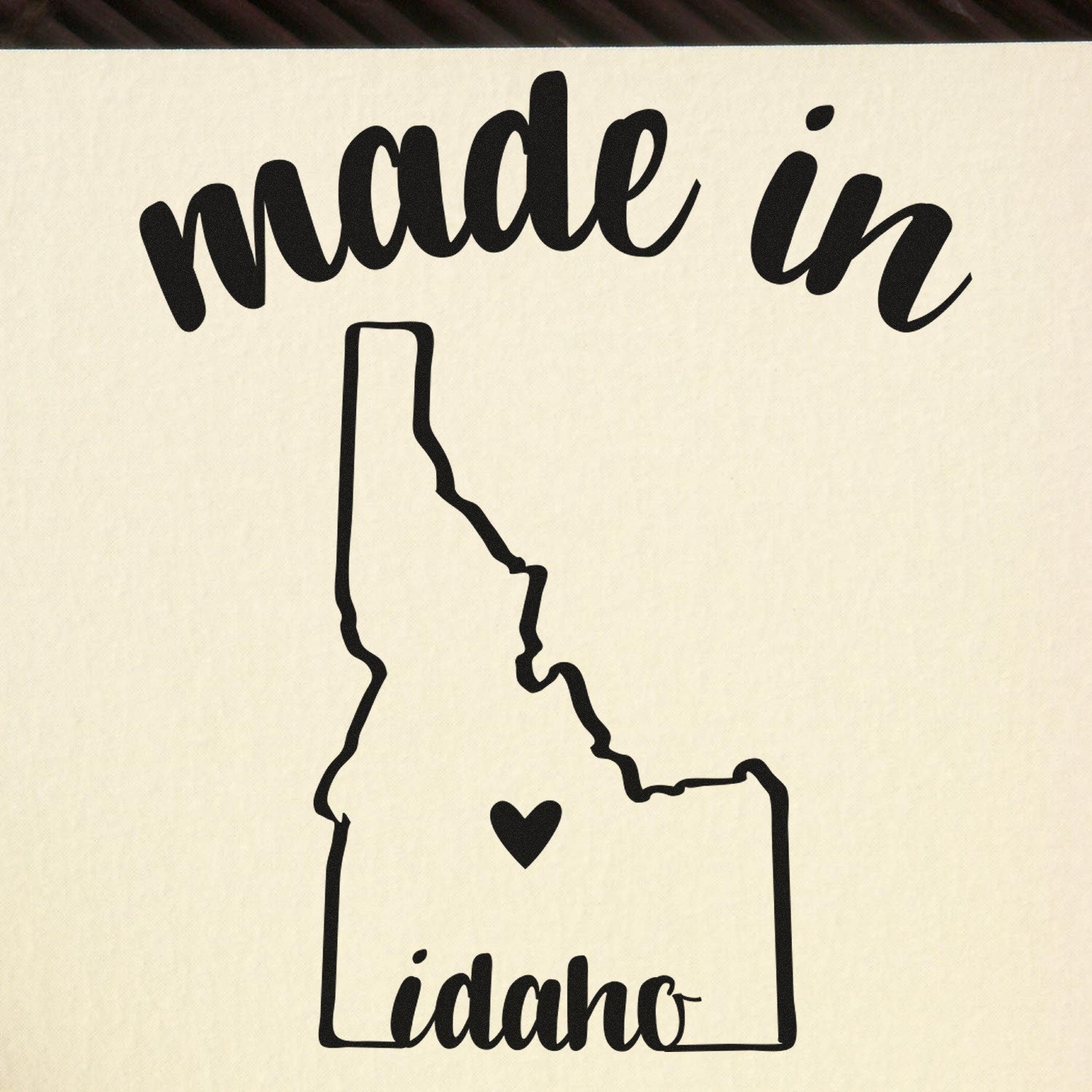 Made with Love in Idaho Rubber Stamp featuring a black outline of Idaho with a heart, and the words 'made in Idaho' in stylish script on a beige background.