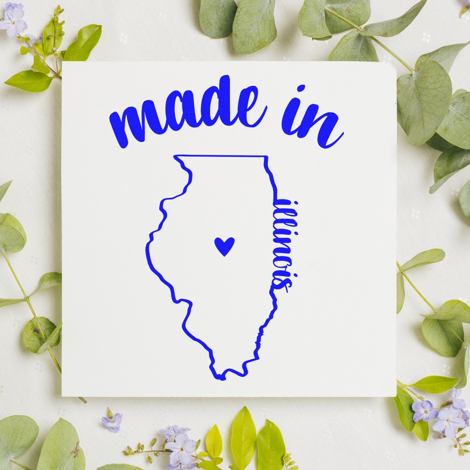 Self-Inking Handmade with Love in Illinois Stamp featuring a blue outline of Illinois with a heart, surrounded by green leaves and purple flowers.