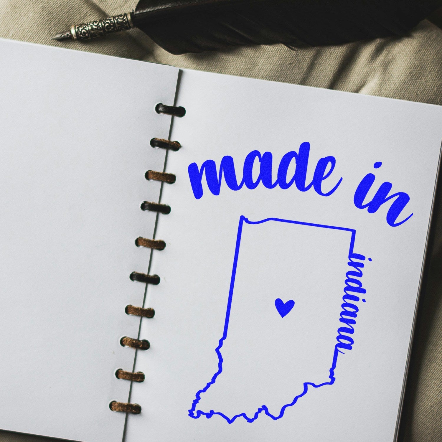 Slim Pre-Inked Stamp Indiana Made in Stamp on open notebook, featuring blue text and Indiana outline with heart, perfect for crafts and stationery.