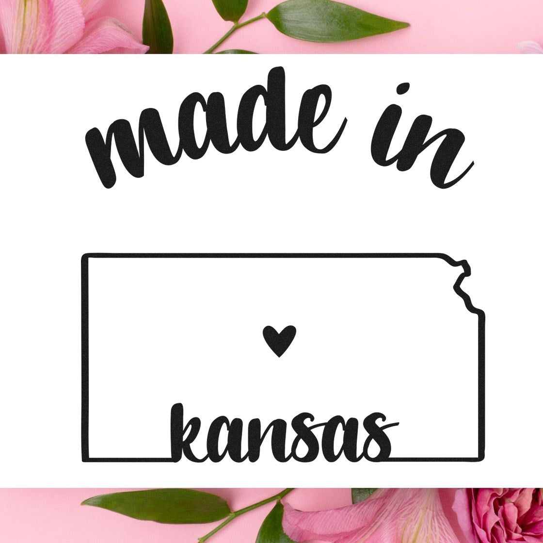 Made in Kansas Stamp Pre-Inked: Black ink stamp with 'made in Kansas' text and state outline, featuring a heart symbol. Perfect for crafts and branding. Pink flowers in the background.