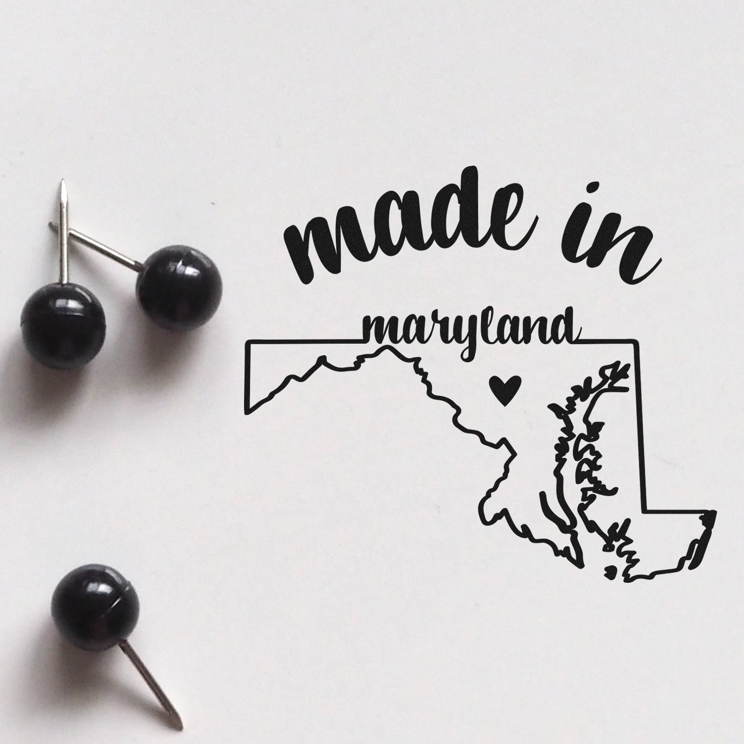 Made with Love in Maryland Rubber Stamp featuring a map outline of Maryland with a heart, alongside black push pins on a white background.