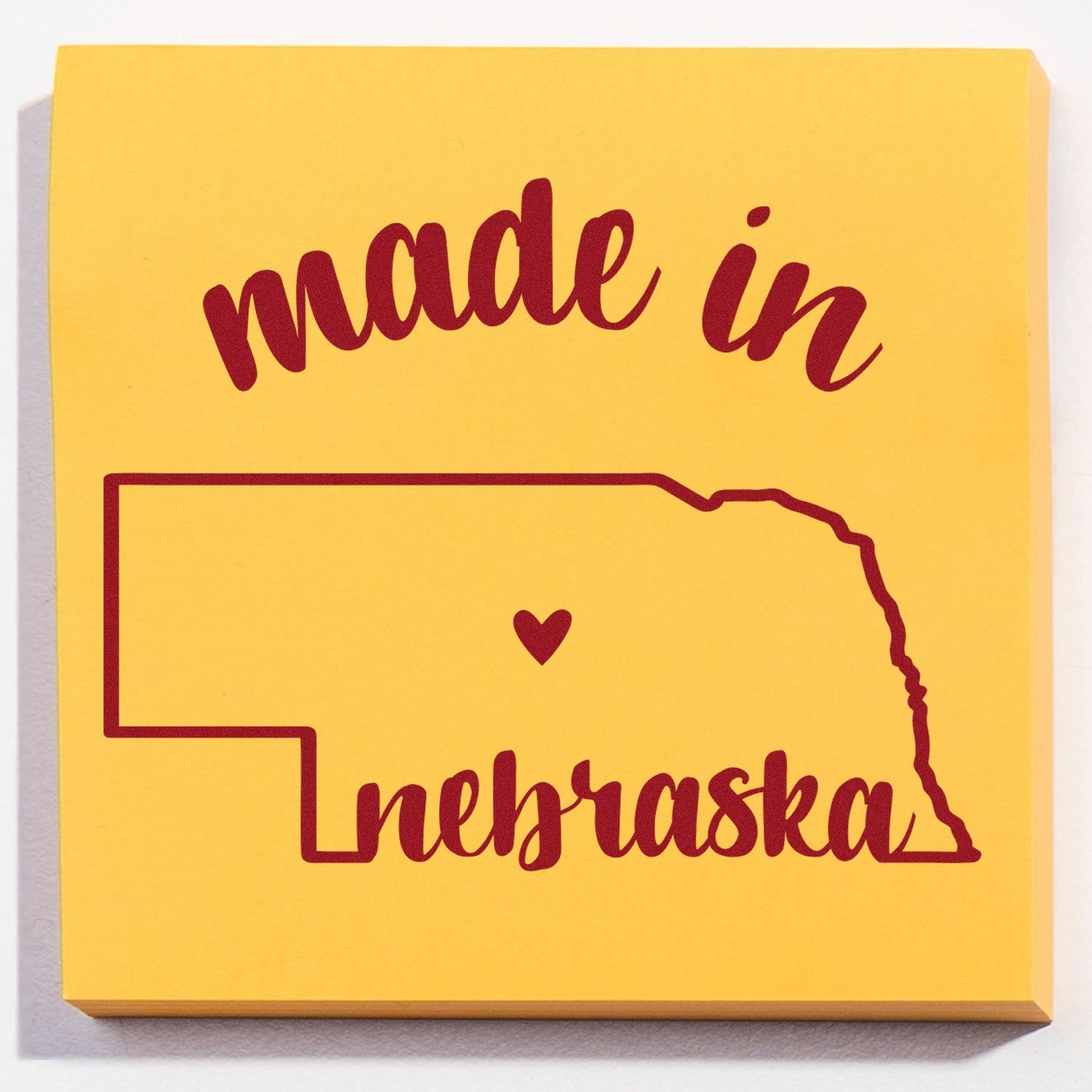 Made with Love in Nebraska Rubber Stamp featuring a yellow square design with red text and a heart inside the outline of Nebraska.