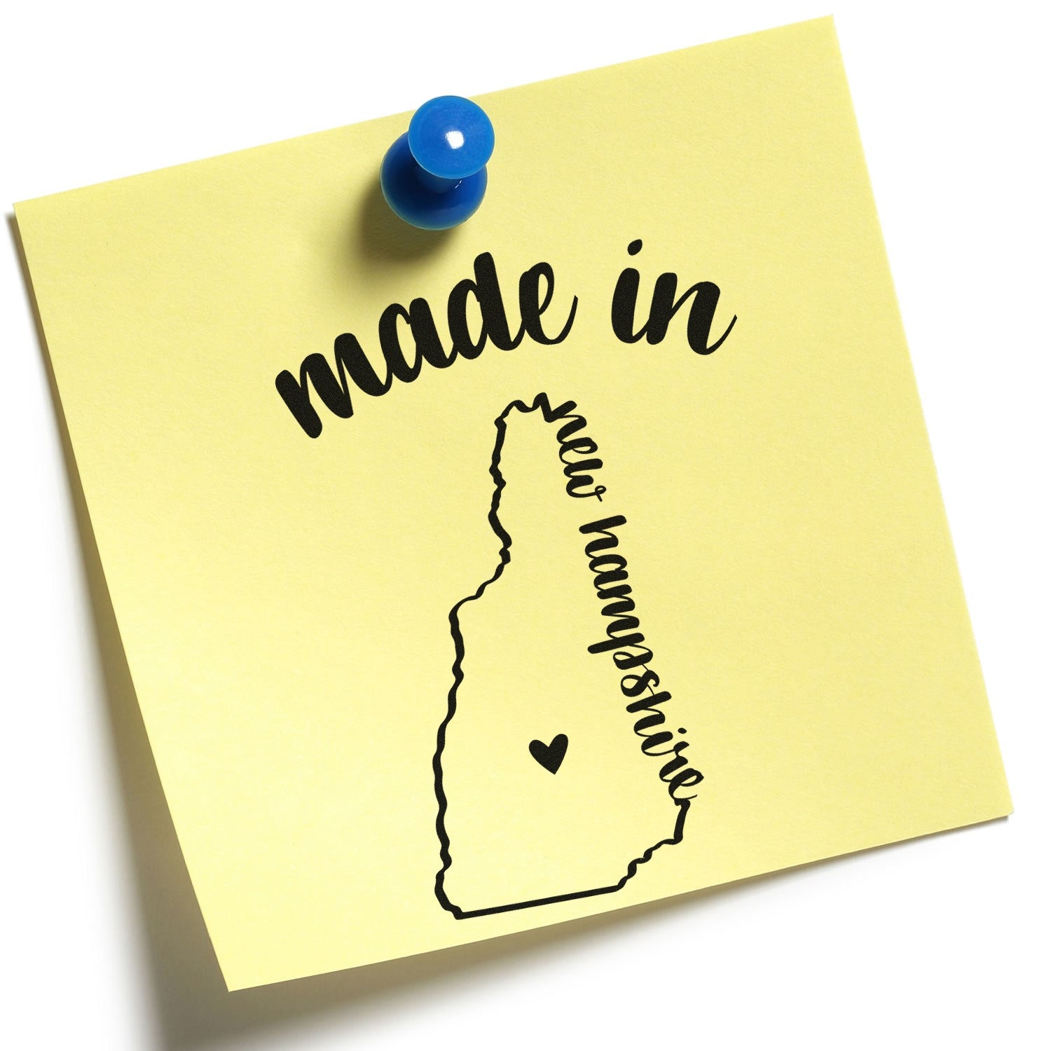 Slim Pre-Inked Stamp New Hampshire Made in Stamp on a yellow sticky note with a blue pushpin, featuring a black outline of New Hampshire and the text made in new hampshire with a heart.