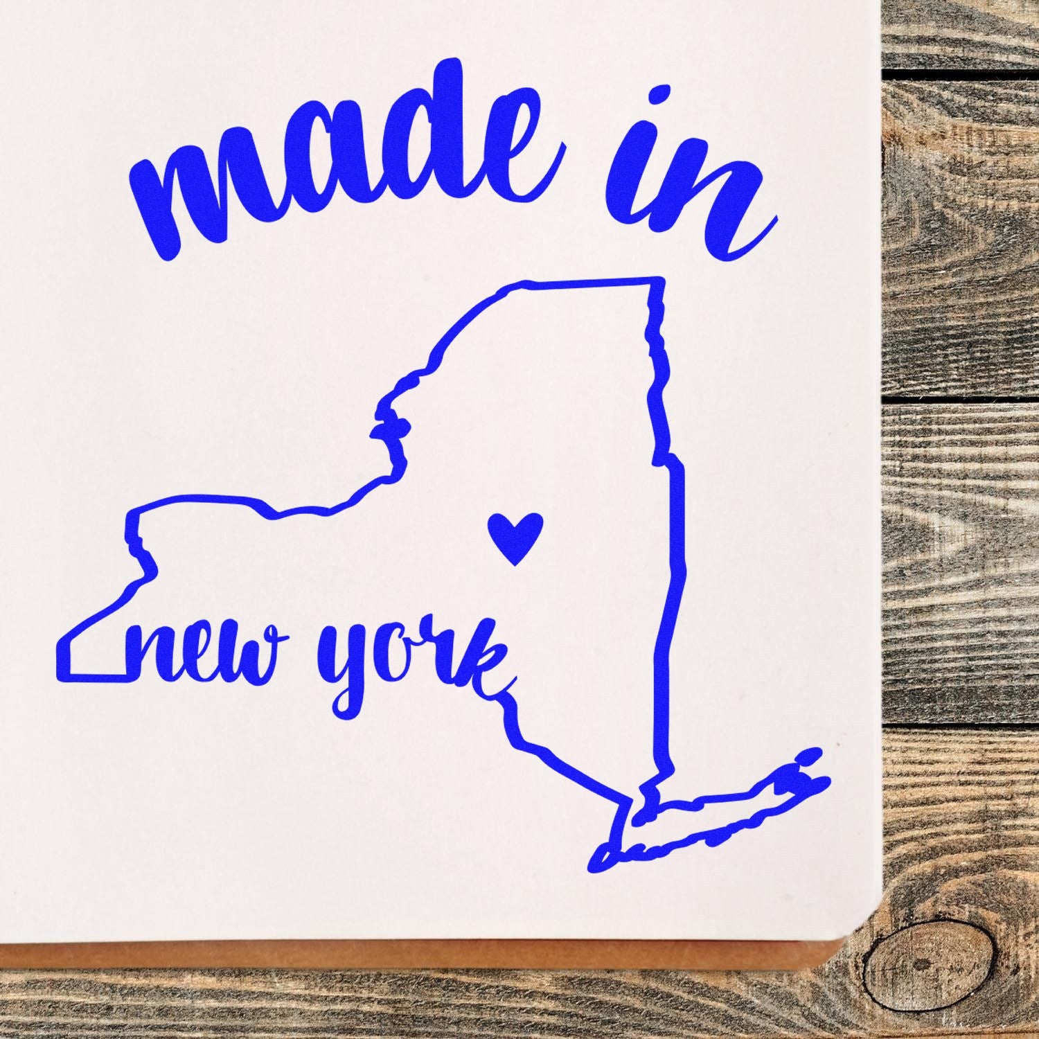 Self-Inking Handmade with Love in New York Stamp featuring a blue outline of New York state with 'made in new york' text and heart symbol on a wooden background.