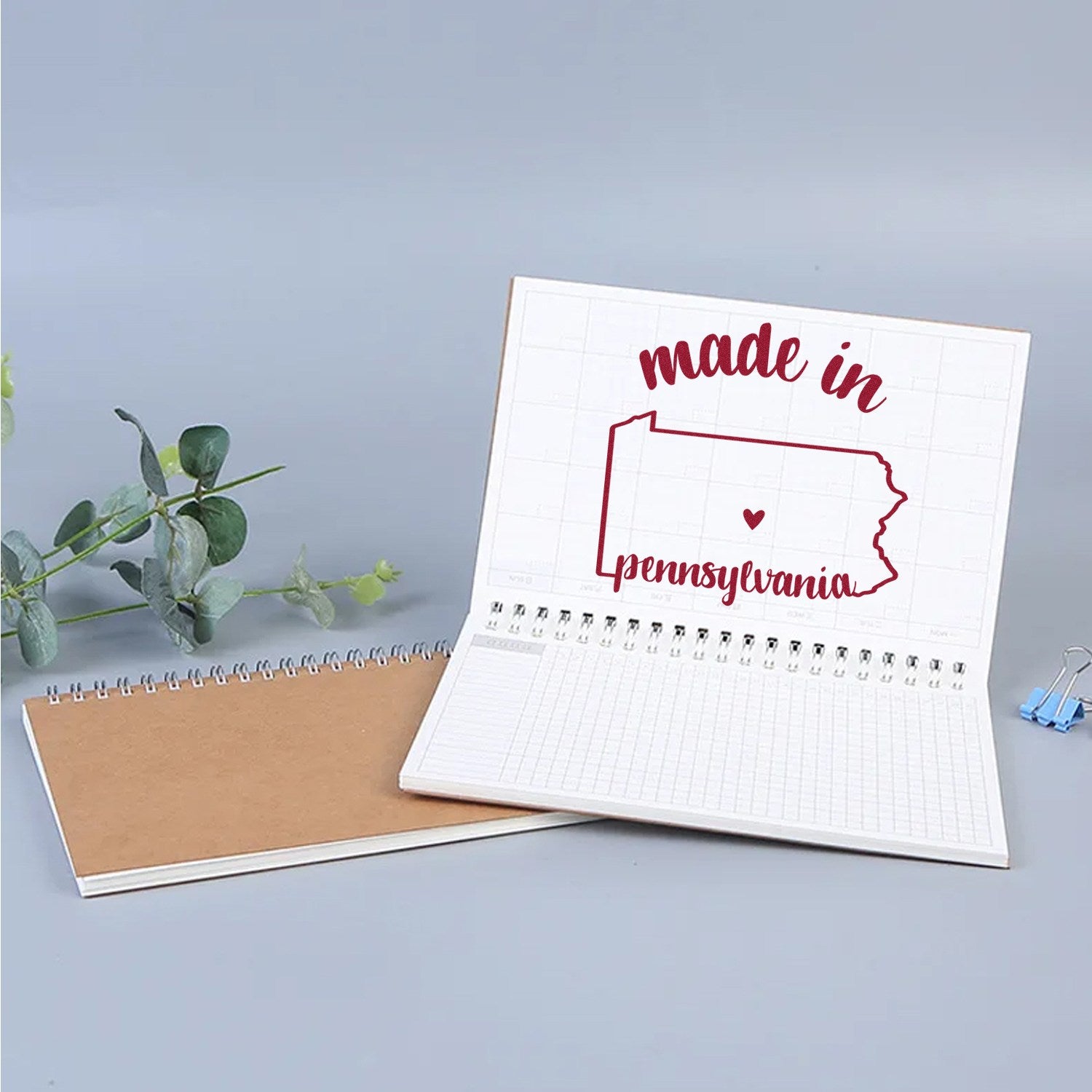 Made in Pennsylvania Stamp Pre-Inked, featuring a red outline of Pennsylvania with 'made in' text, displayed on an open notebook with a plant and paper clips nearby.