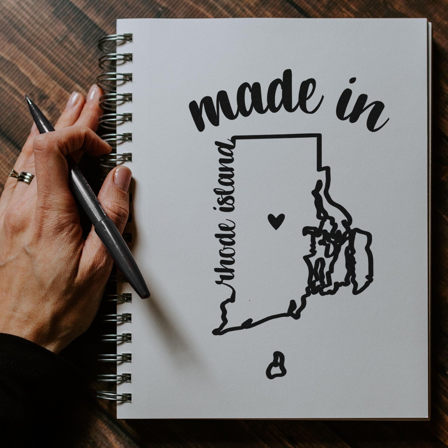 Made with Love in Rhode Island Rubber Stamp on a notebook, featuring a heart and state outline design, perfect for crafts and gifts.