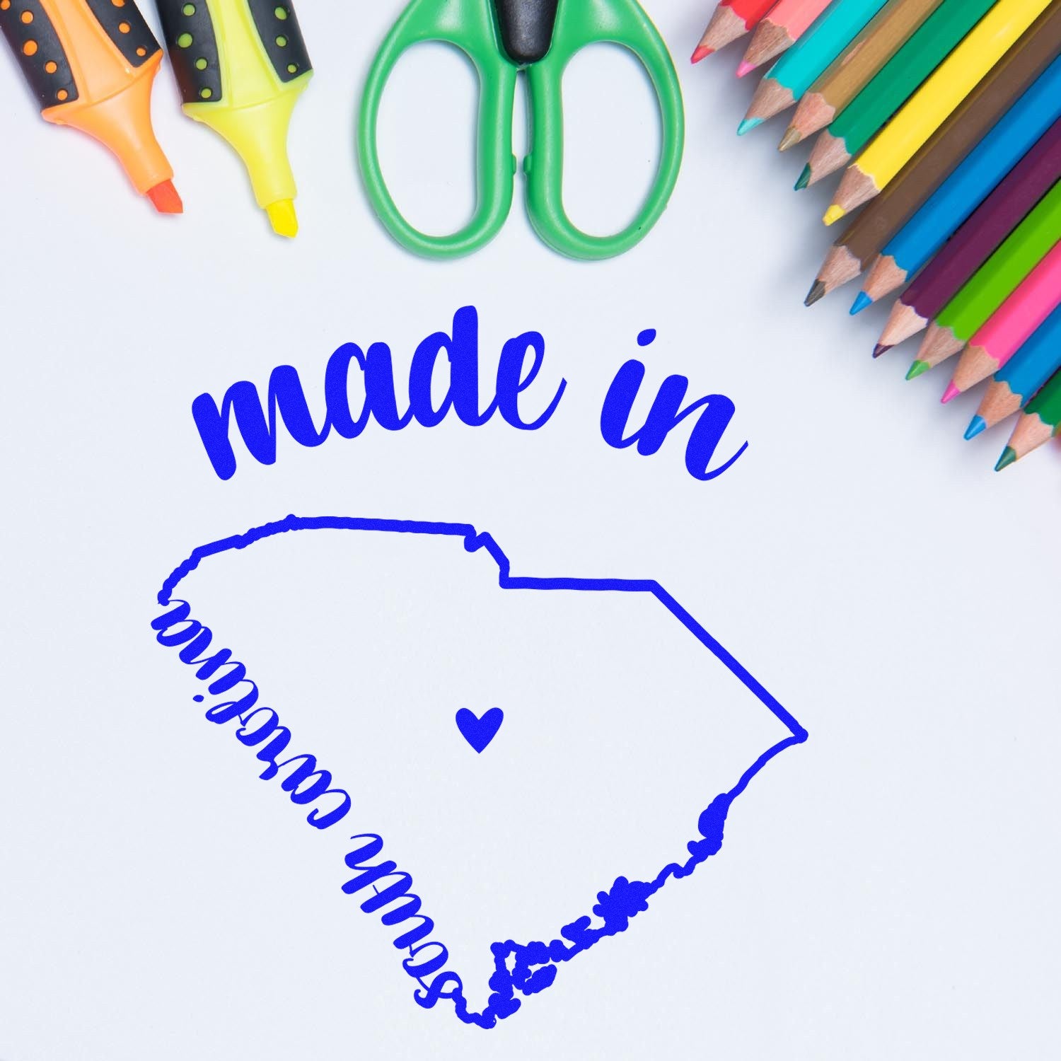 Slim Pre-Inked Stamp South Carolina Made in Stamp featuring a blue outline of South Carolina with made in text, surrounded by colorful markers, scissors, and pencils on a white background.