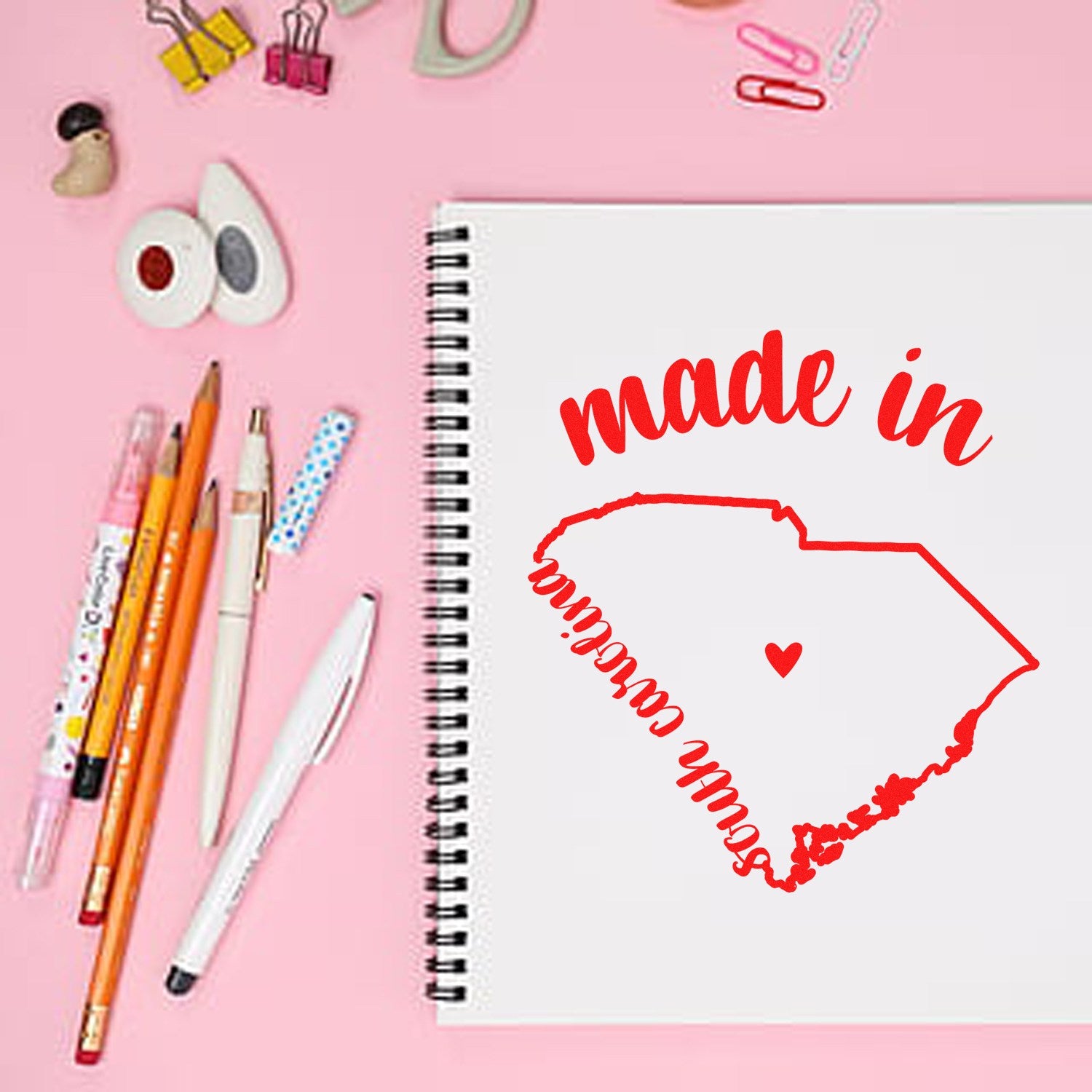 Self-Inking Handmade with Love in South Carolina Stamp on a pink desk with stationery, featuring a red outline of South Carolina and 'made in' text. Perfect for crafts and gifts.