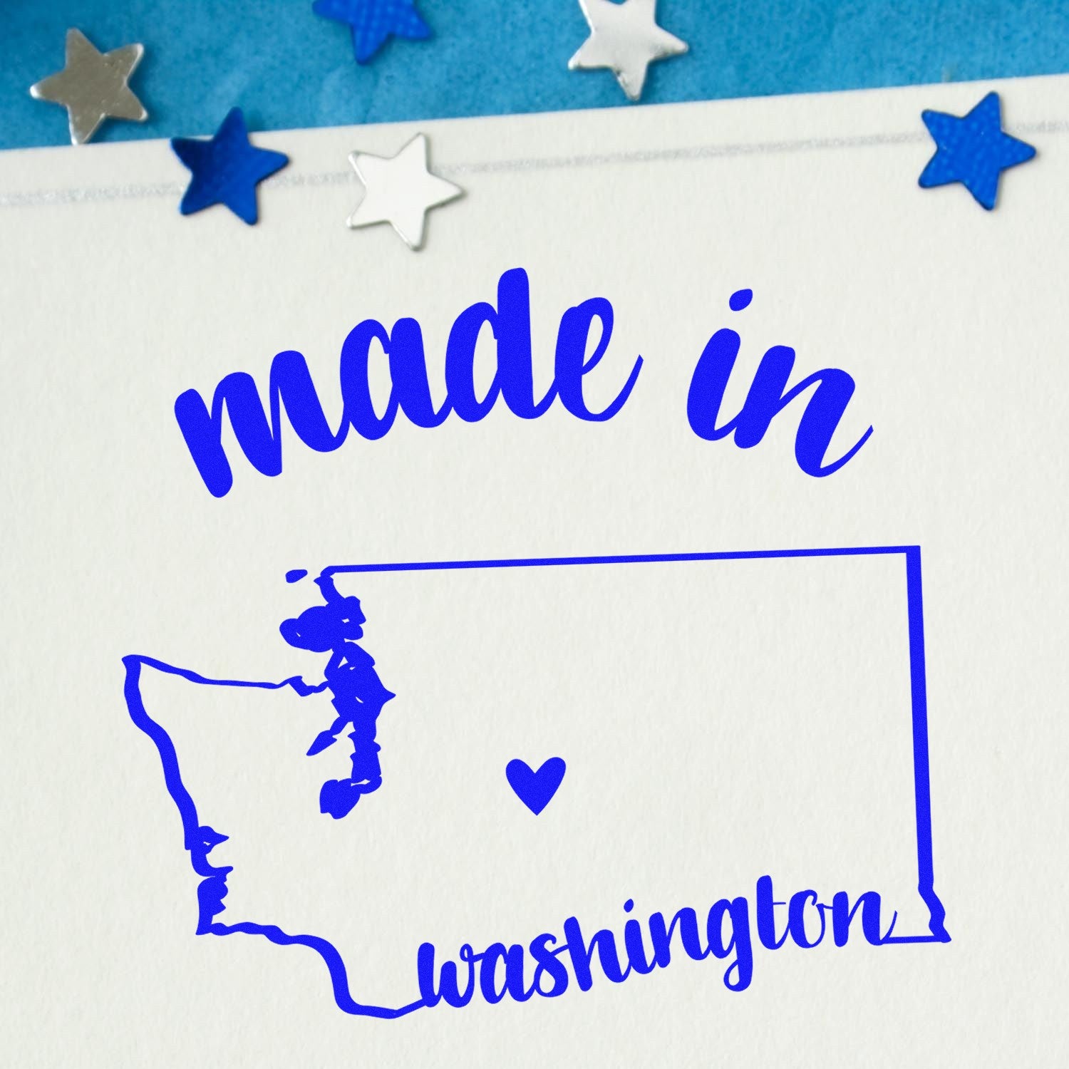 Self-Inking Handmade with Love in Washington Stamp featuring a blue outline of Washington state with a heart, surrounded by stars on a white background.