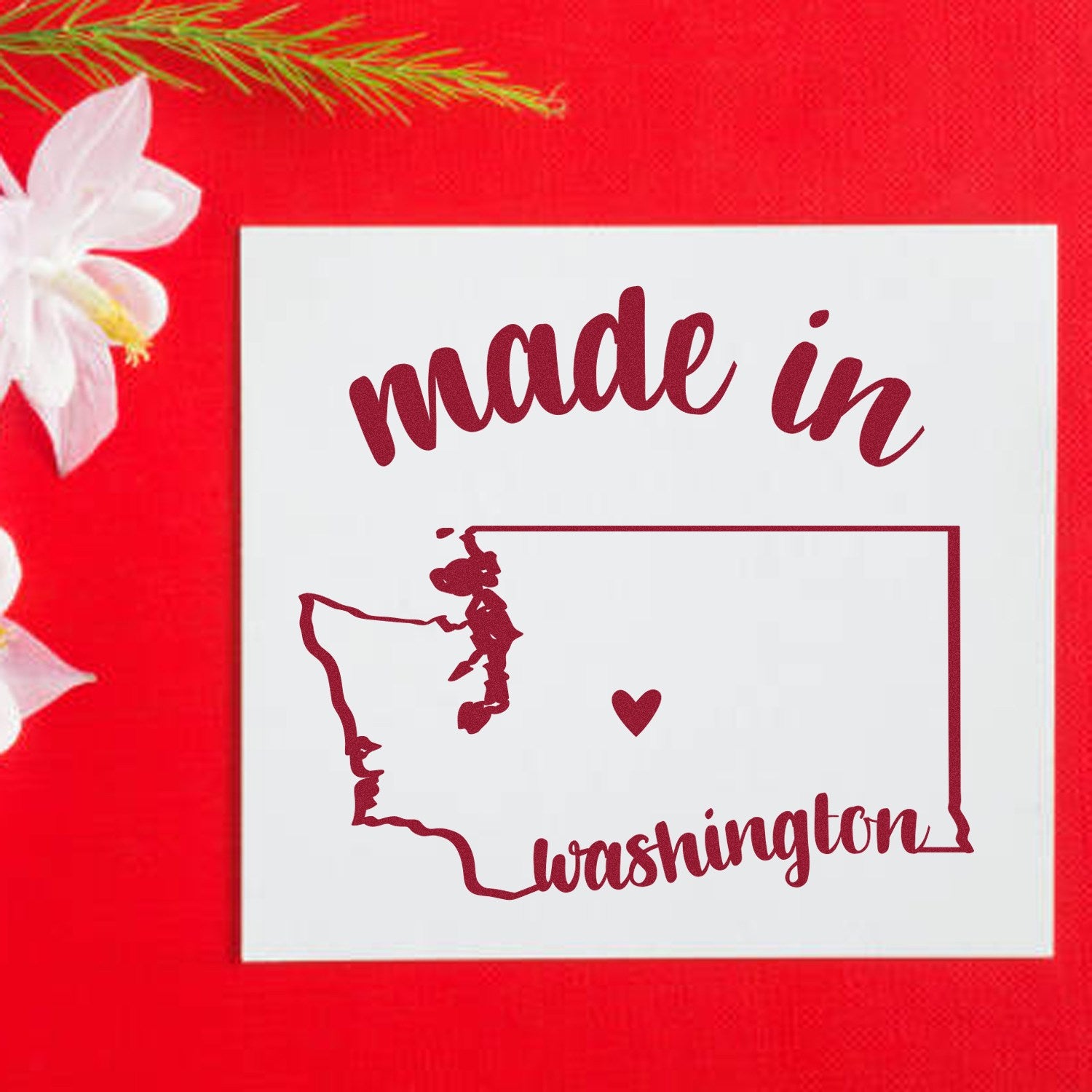 Made with Love in Washington Rubber Stamp featuring a red outline of Washington state with a heart, set against a red background with white flowers. Perfect for crafts and gifts.