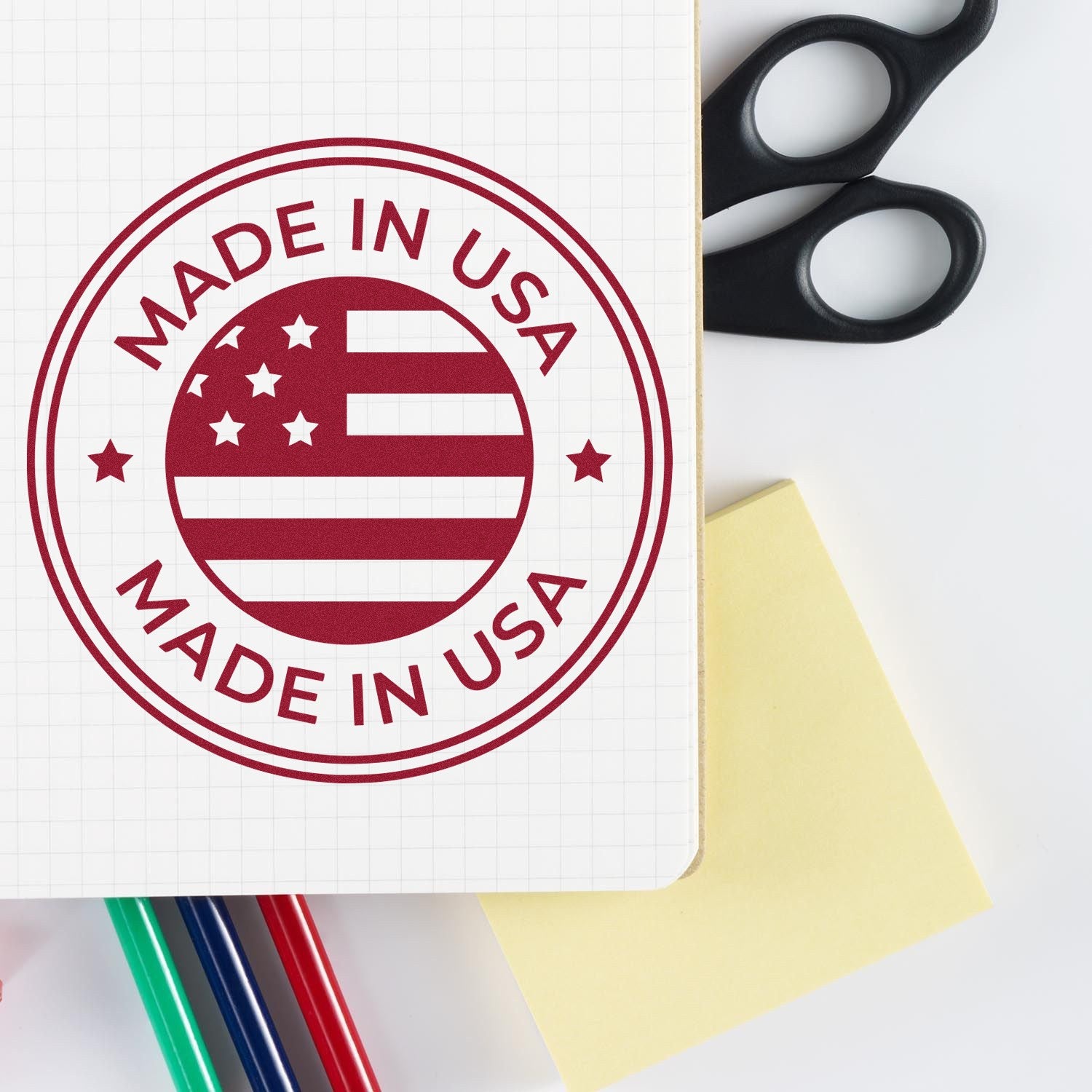 PSI Pre-Inked Patriotic Seal Stamp featuring 'Made in USA' design with stars and stripes, shown on a notebook with colorful pens and scissors nearby.