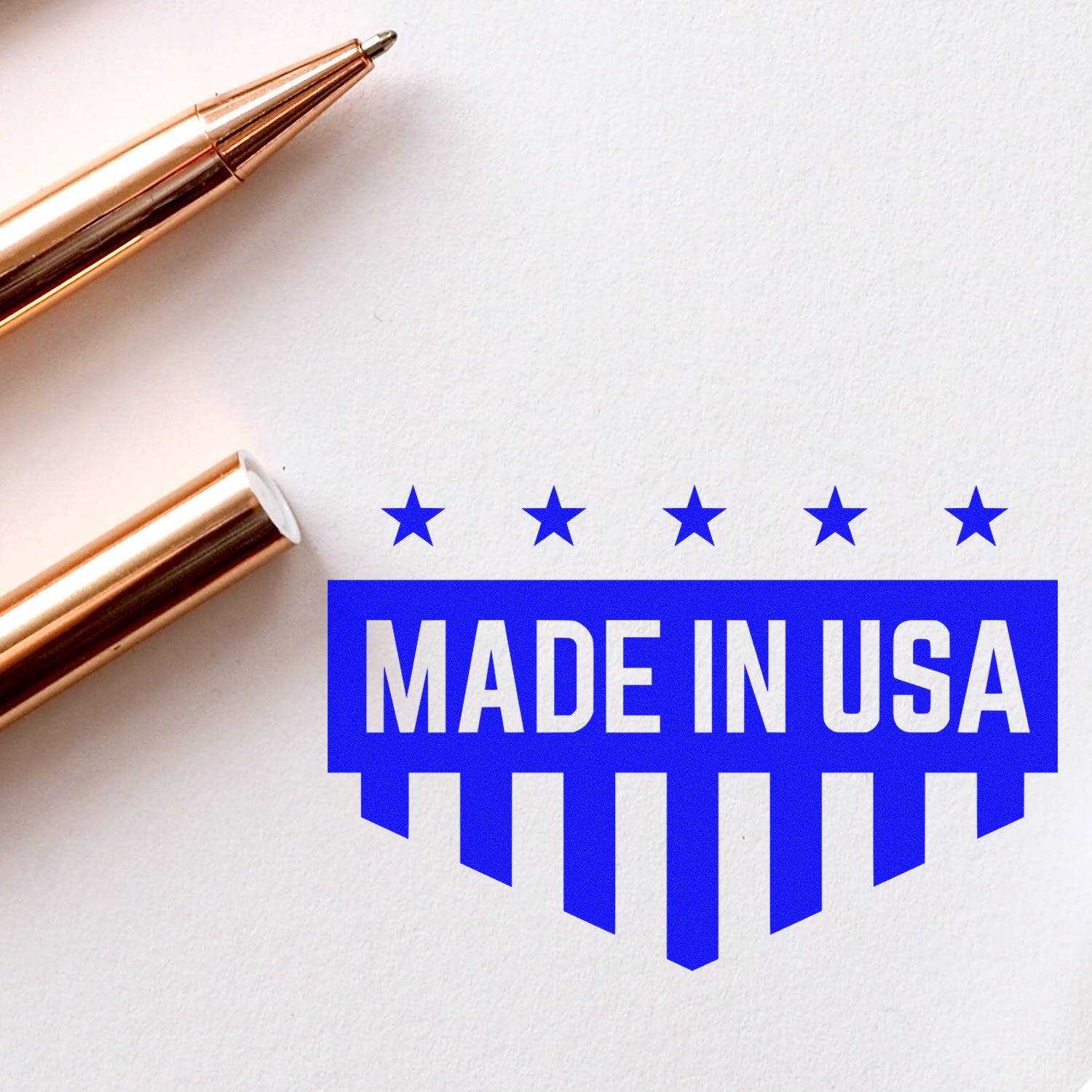 Self-Inking Patriotic Quality Seal Stamp with 'Made in USA' design in blue, featuring stars and stripes, next to a gold pen on white paper.