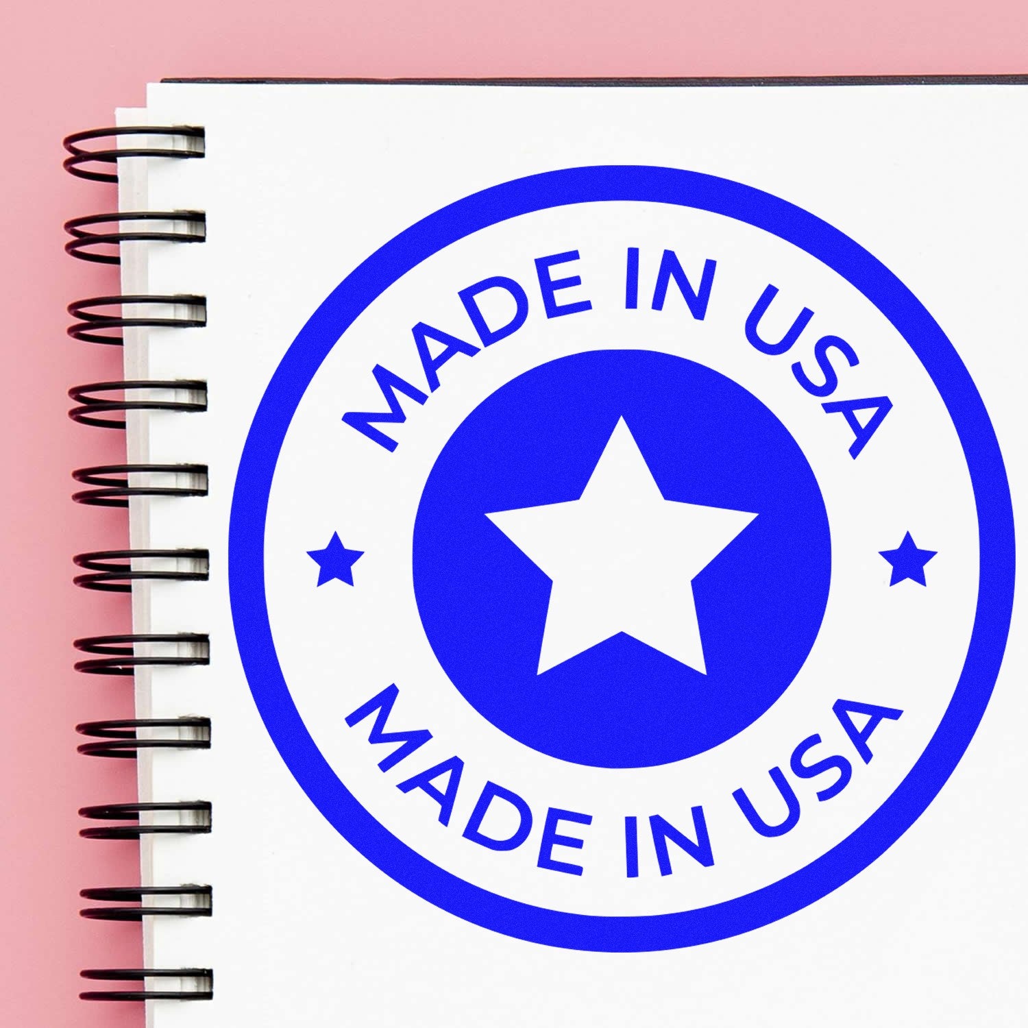 PSI Pre-Inked Our Country Craftsmanship Seal Stamp featuring a blue Made in USA design with a star, displayed on a spiral notebook against a pink background.