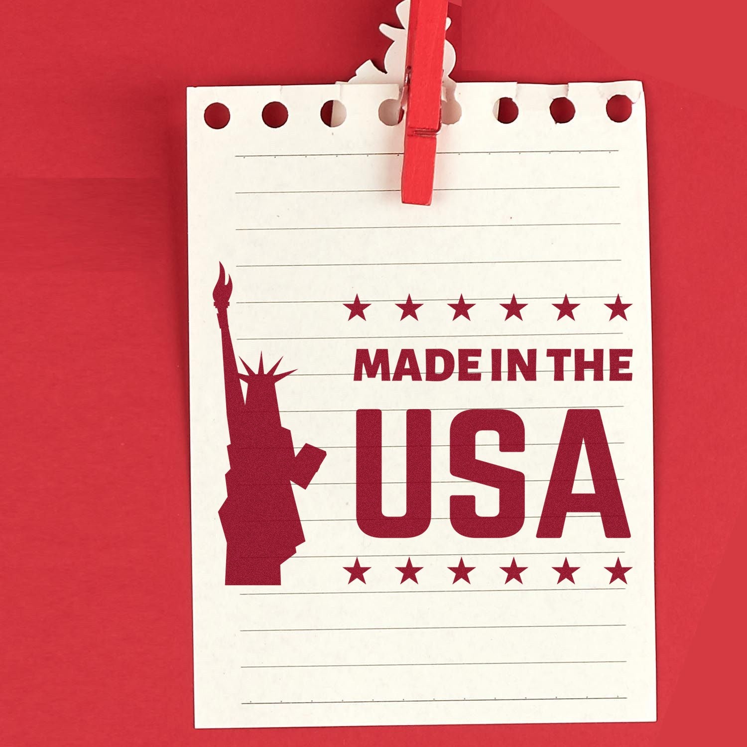 Image of Slim Pre-Inked Liberty Made In The USA Stamp on red background, featuring a stamped design with the Statue of Liberty silhouette and Made in the USA text on lined paper.