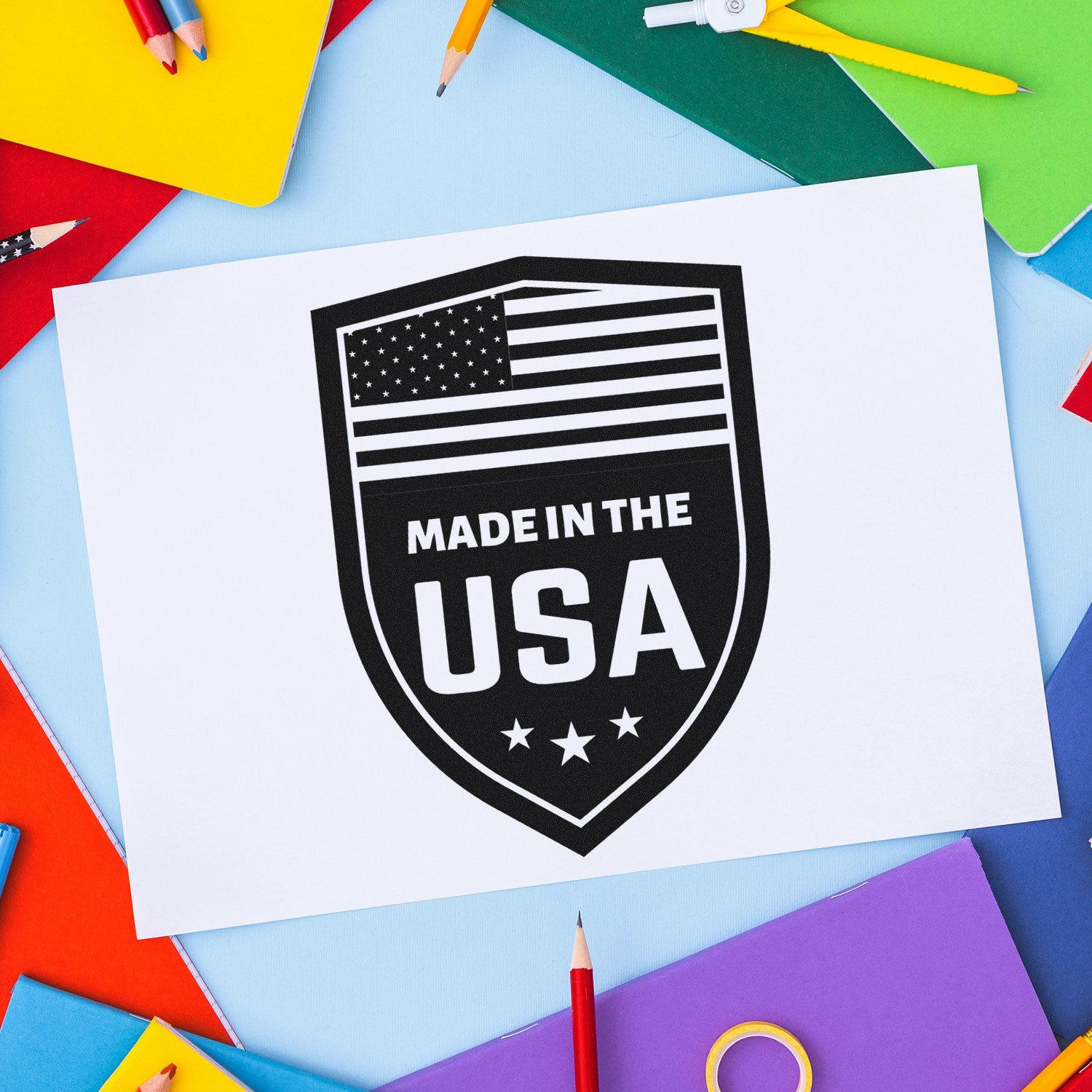 Slim Pre-Inked Proudly Made In The USA Stamp on colorful paper background, featuring a black shield design with stars and stripes, emphasizing American craftsmanship.