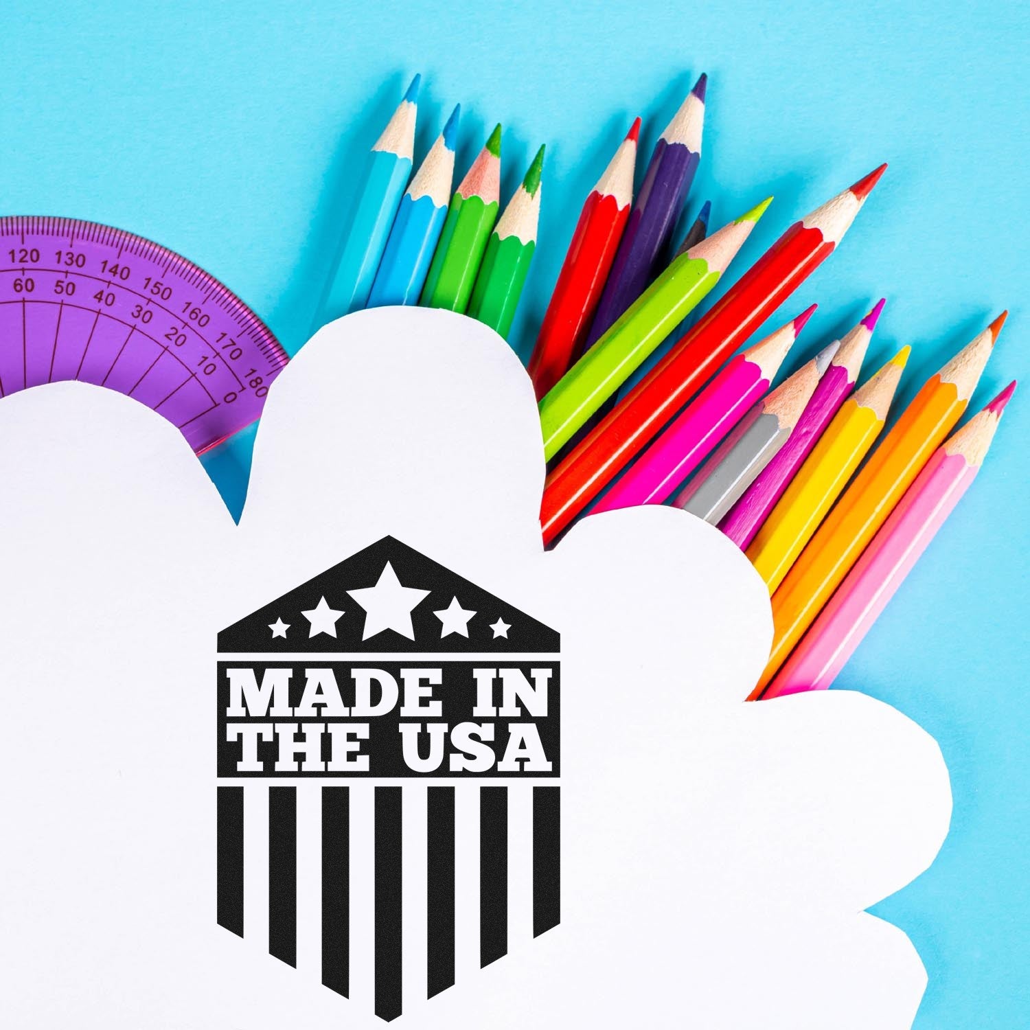 Slim Pre-Inked Patriotic Pride Seal Stamp with 'Made in the USA' design, featuring stars and stripes, next to colorful pencils on a blue background.