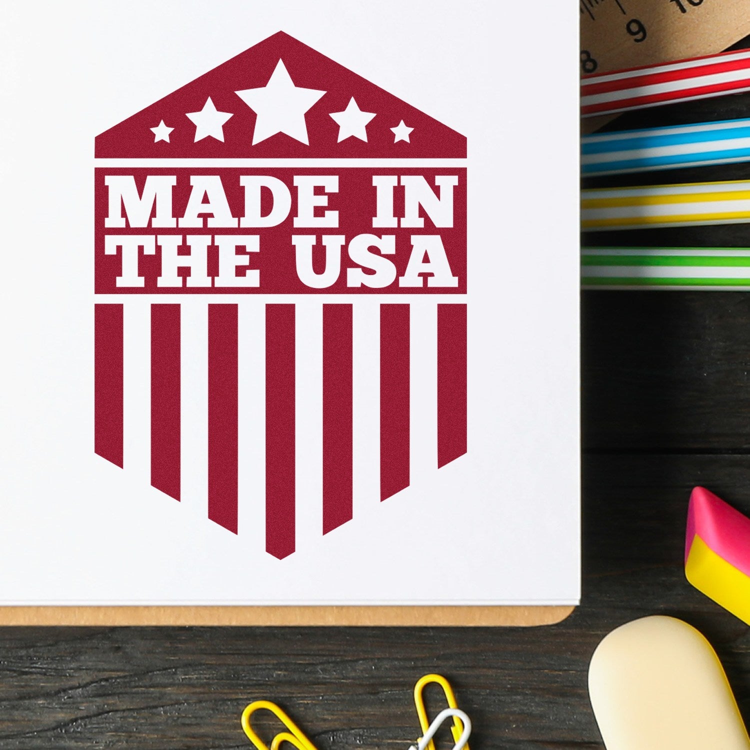 Wood Handle Patriotic Pride Seal Rubber Stamp featuring Made in the USA design with stars and stripes, shown on a notebook. Ideal for adding a patriotic touch to crafts and documents.