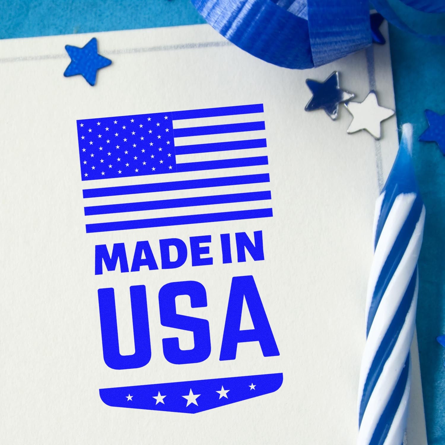 Slim Pre-Inked Made In USA Emblem Stamp with blue American flag design on paper, surrounded by blue stars and ribbon.