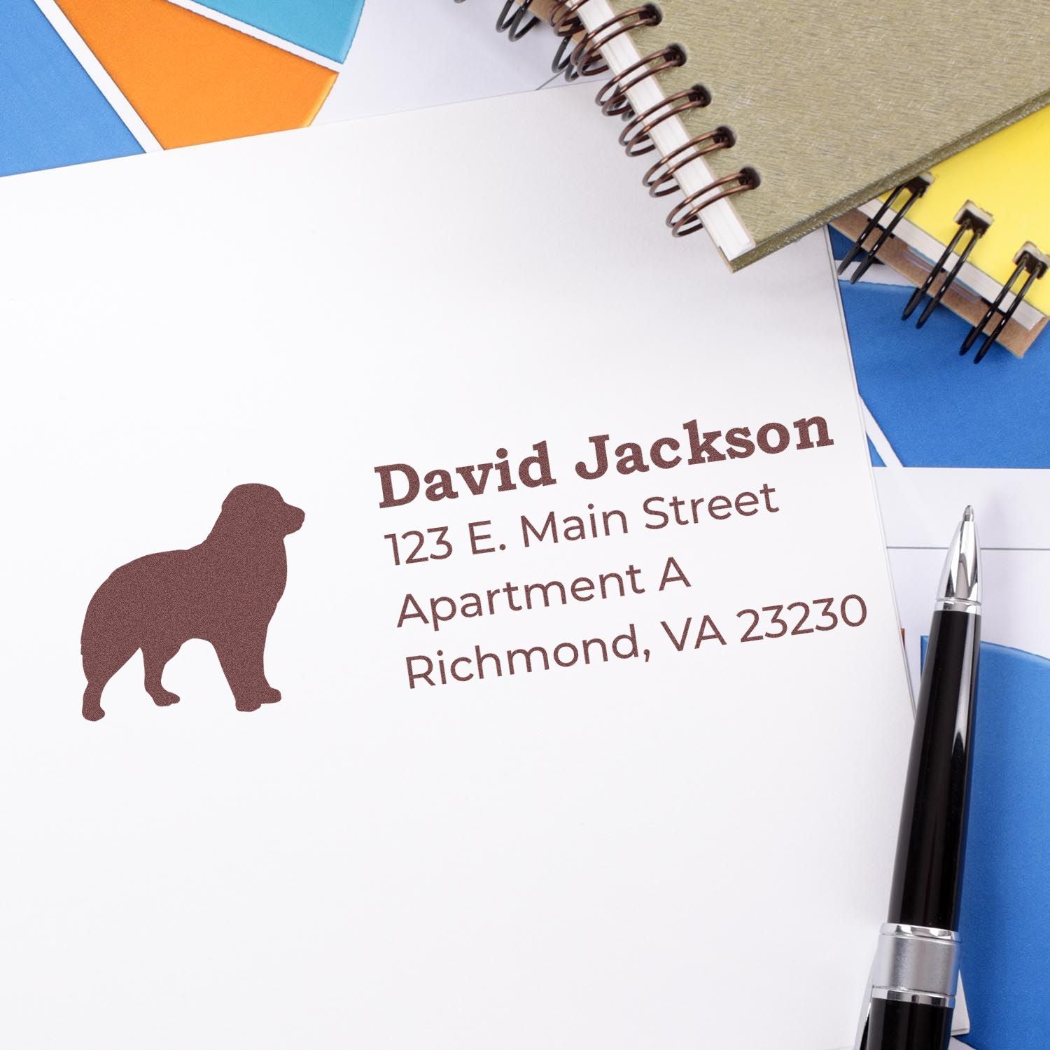 Slim Pre-Inked Australian Shepherd Address Stamp on white paper with a brown dog silhouette, personalized with name and address. Surrounded by colorful folders, a notebook, and a pen.