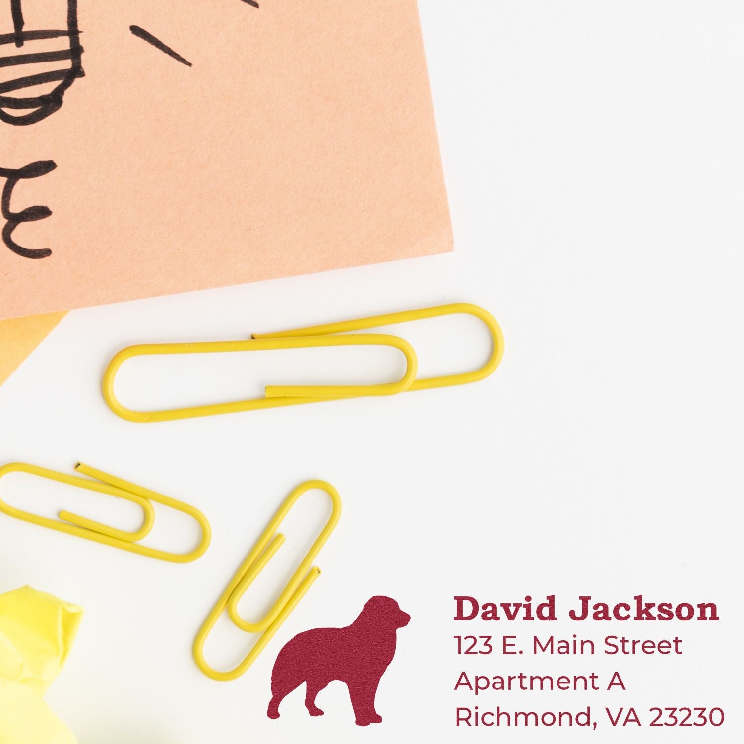 Slim Pre-Inked Australian Shepherd Address Stamp on paper with yellow paperclips, featuring a red dog silhouette and address details in bold red font.