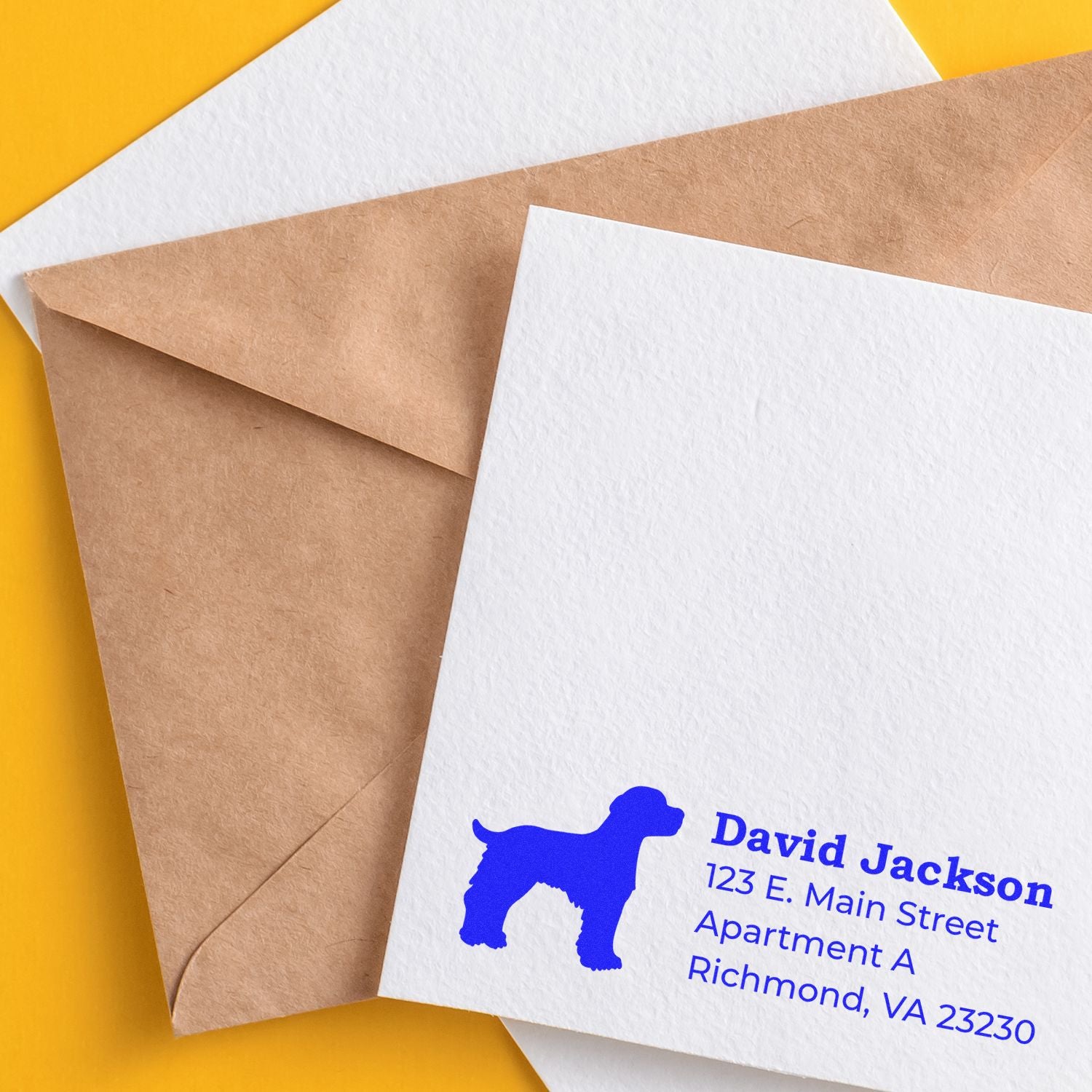 Brittany Spaniel Silhouette Address Rubber Stamp on a white envelope with a blue dog silhouette and address details, placed on a yellow surface with a brown envelope.