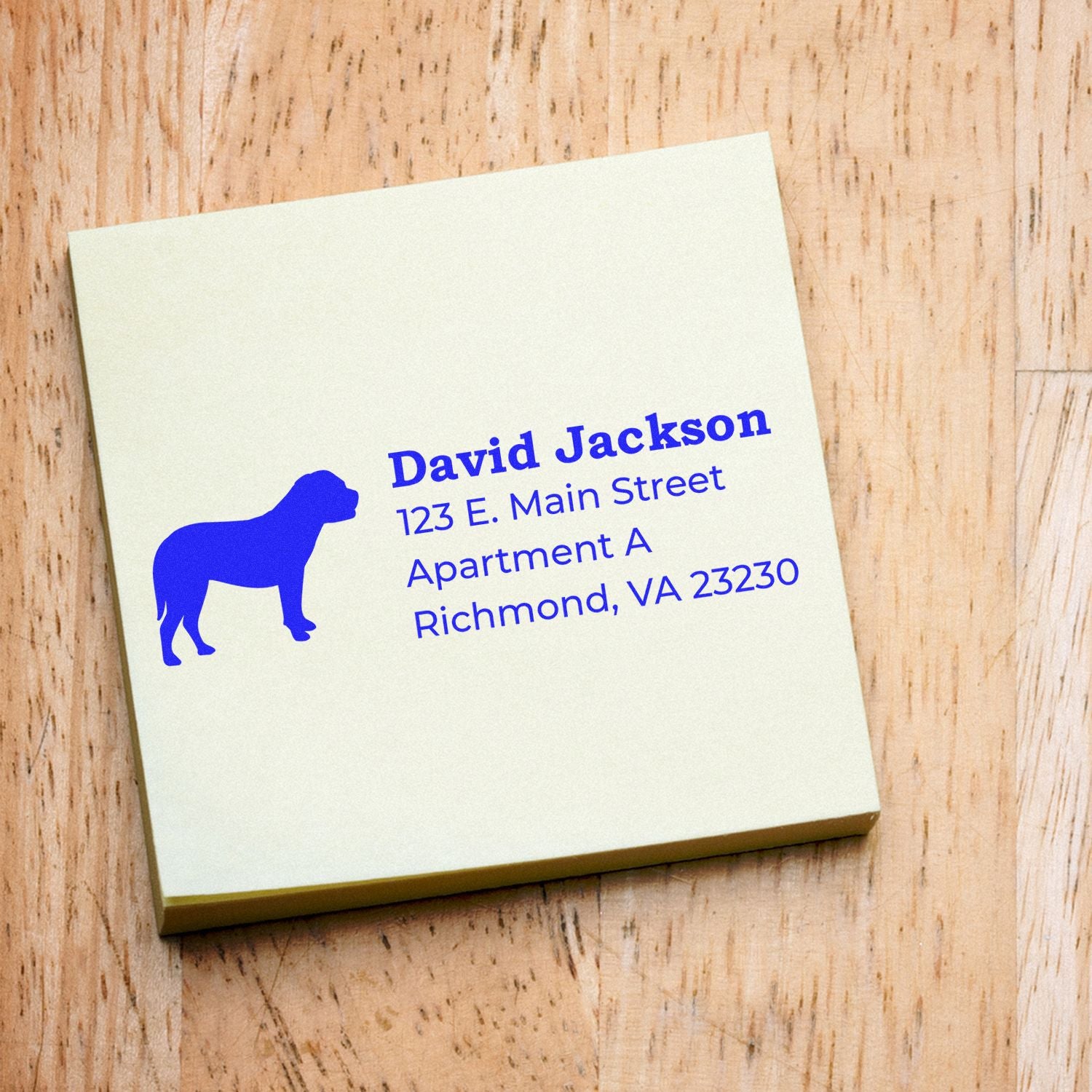 Self-Inking Bullmastiff Dog Address Stamp on a notepad, featuring a blue bullmastiff silhouette and sample address text in blue ink on a wooden surface.