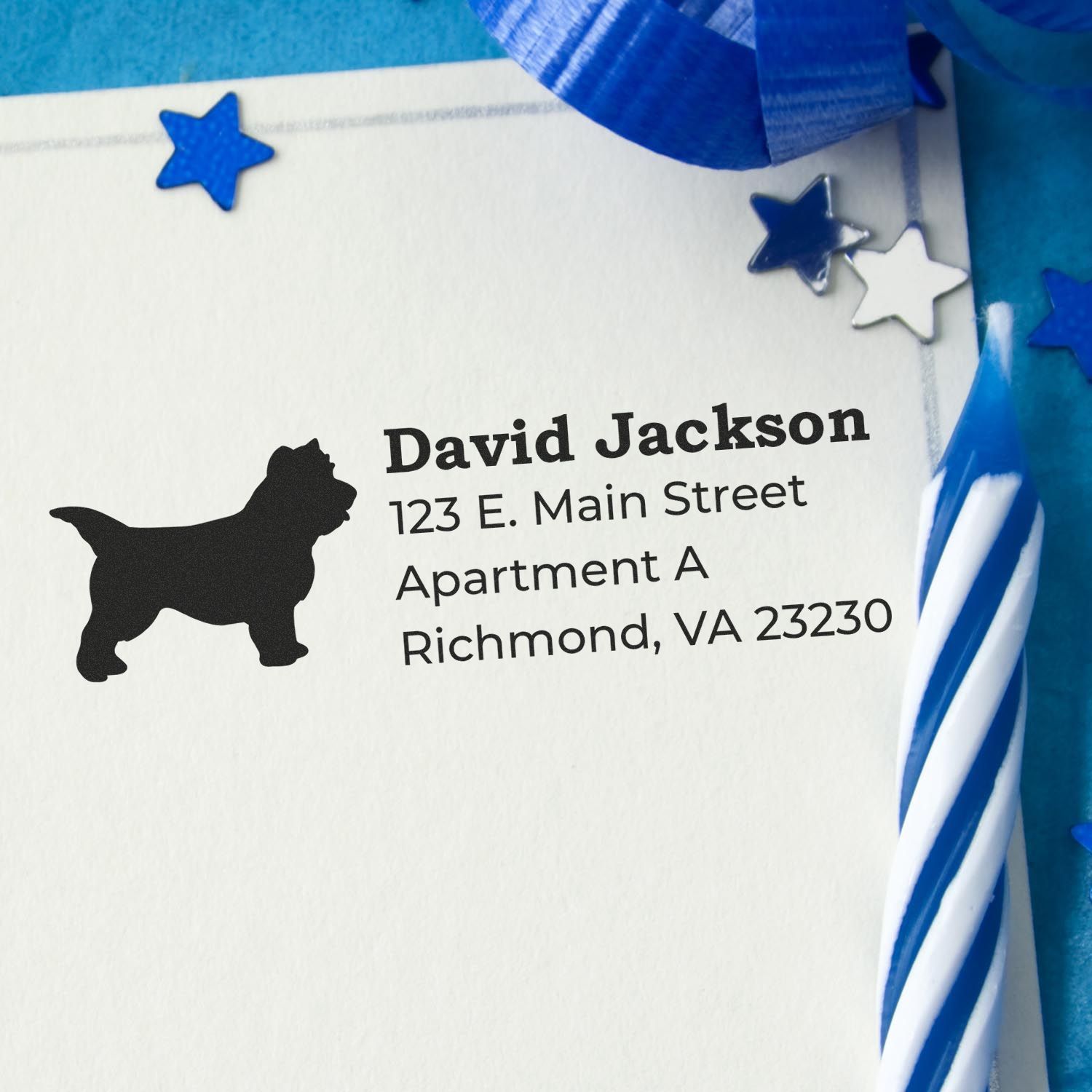 PSI Pre-Inked Personalized Cairn Terrier Address Stamp on a card with a silhouette of a dog, surrounded by blue stars and a striped candle, showcasing a sample address.