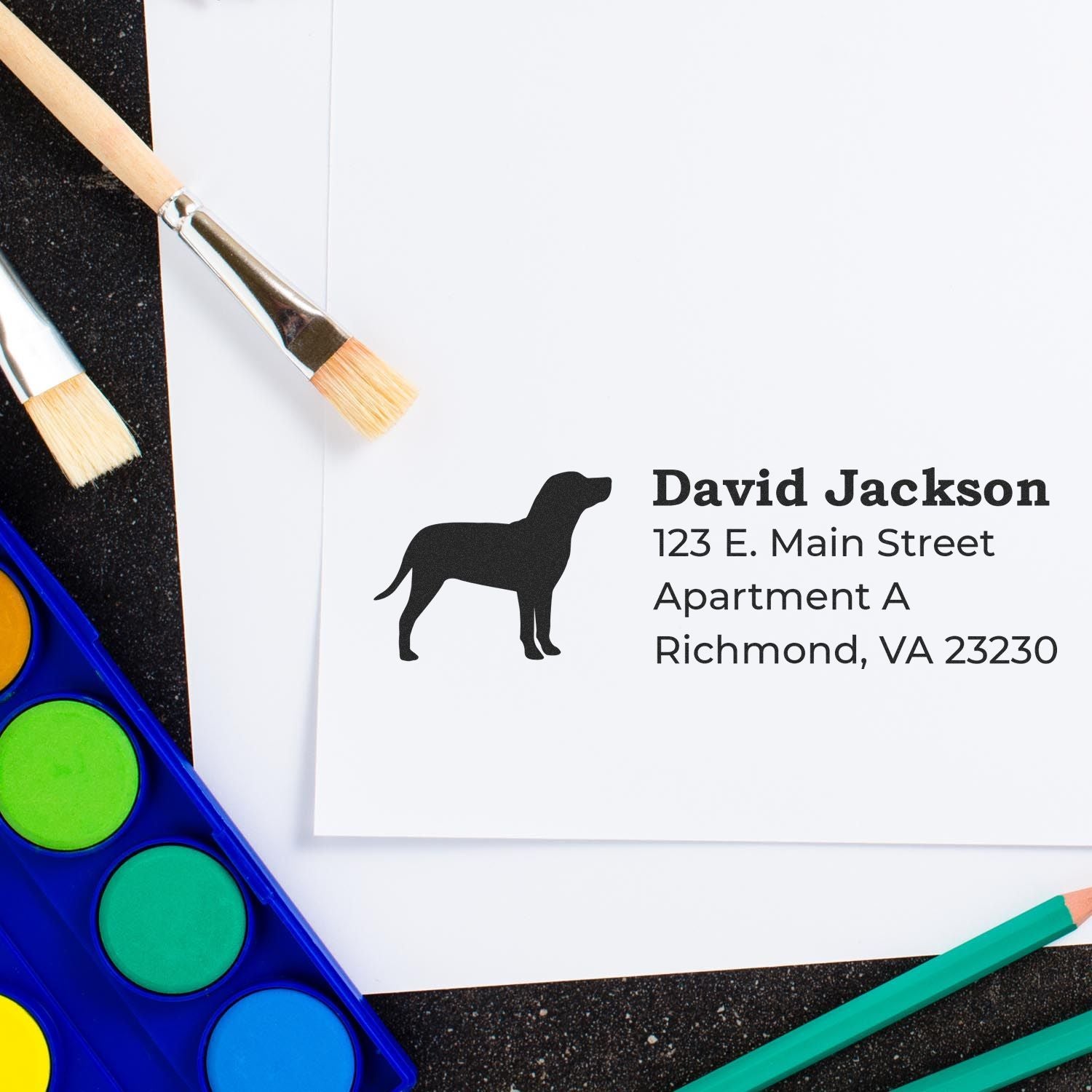 Self-Inking Catahoula Dog Address Stamp on white paper with a silhouette of a dog, surrounded by paintbrushes and watercolor paints.