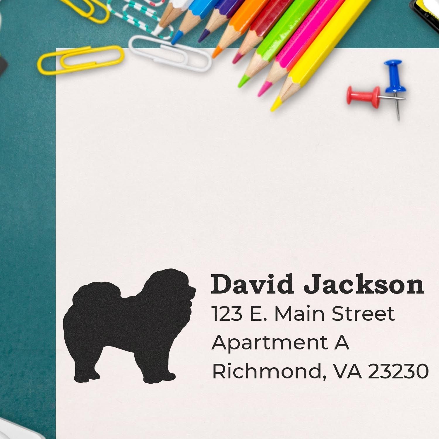 PSI Pre-Inked Personalized Chow Address Stamp on paper with colorful pencils and paperclips. Features a Chow silhouette and sample address text.