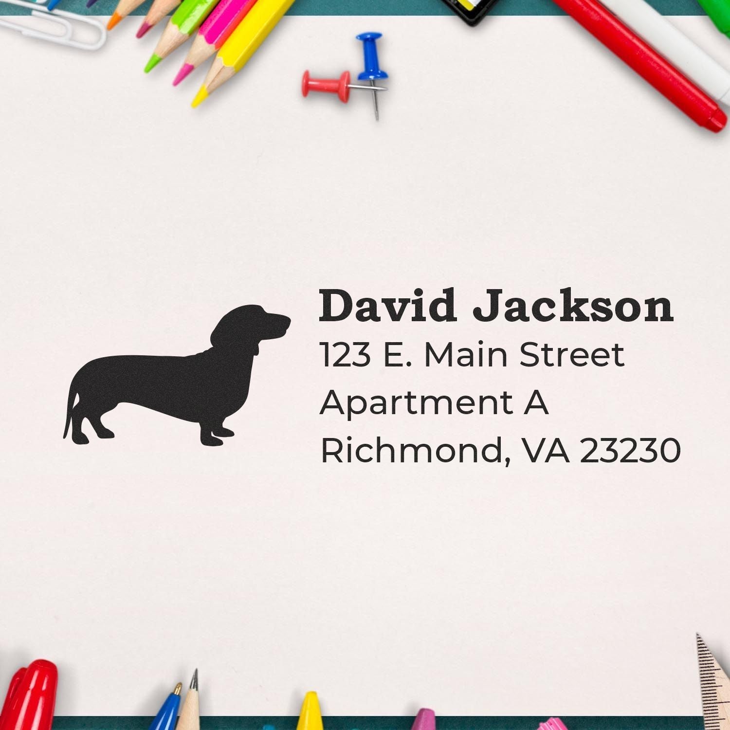 Self-Inking Dachshund Dog Address Stamp on white paper surrounded by colorful stationery, featuring a dachshund silhouette and sample address text.