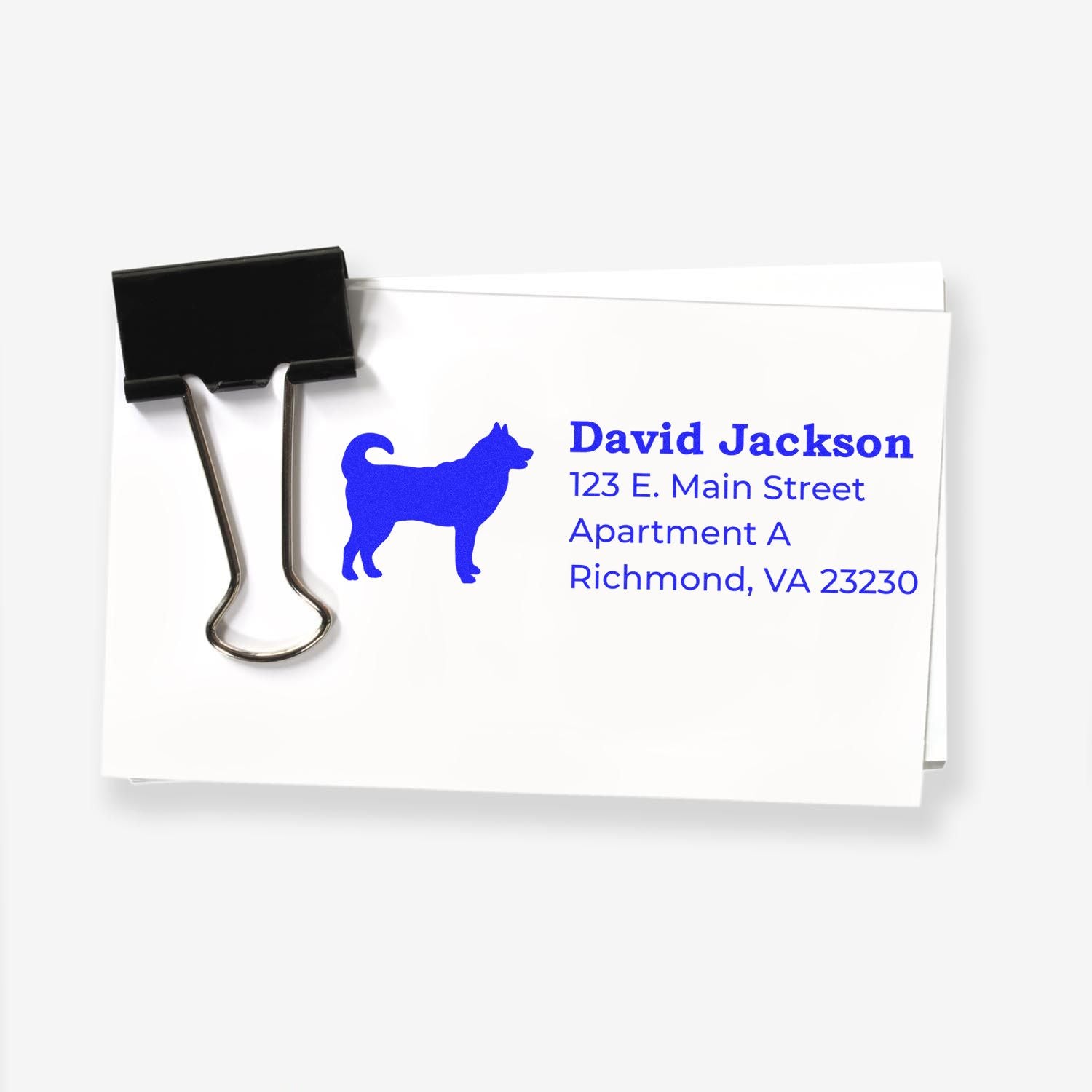 A stack of envelopes with a blue husky silhouette and address details stamped using the Self-Inking Husky Dog Address Stamp, secured by a black binder clip.