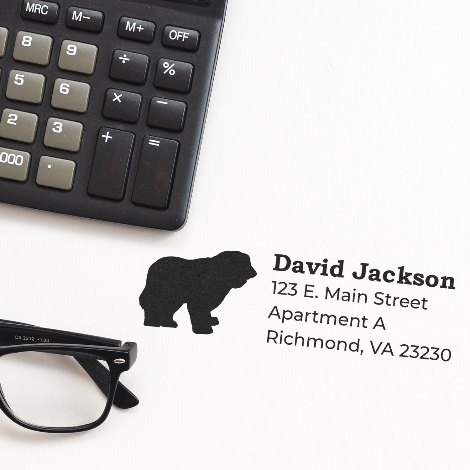 Self-Inking Old English Sheepdog Dog Address Stamp on paper next to a calculator and glasses, featuring a silhouette of the dog and an address in bold, clear font.