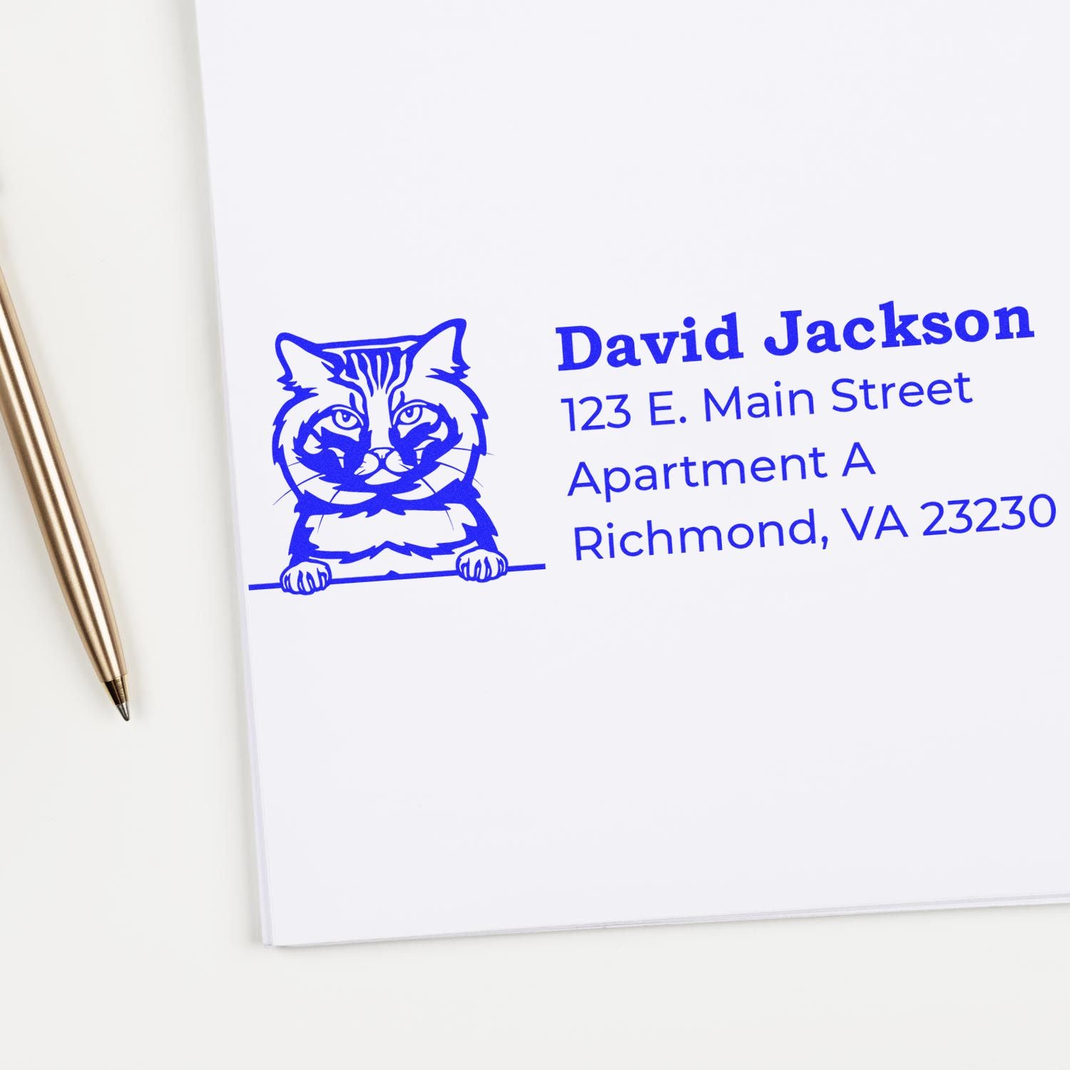 Blue ink impression of a Wood Handle American Bobtail Cat Address Stamp on white paper, featuring a cat illustration and sample address. Pen nearby.