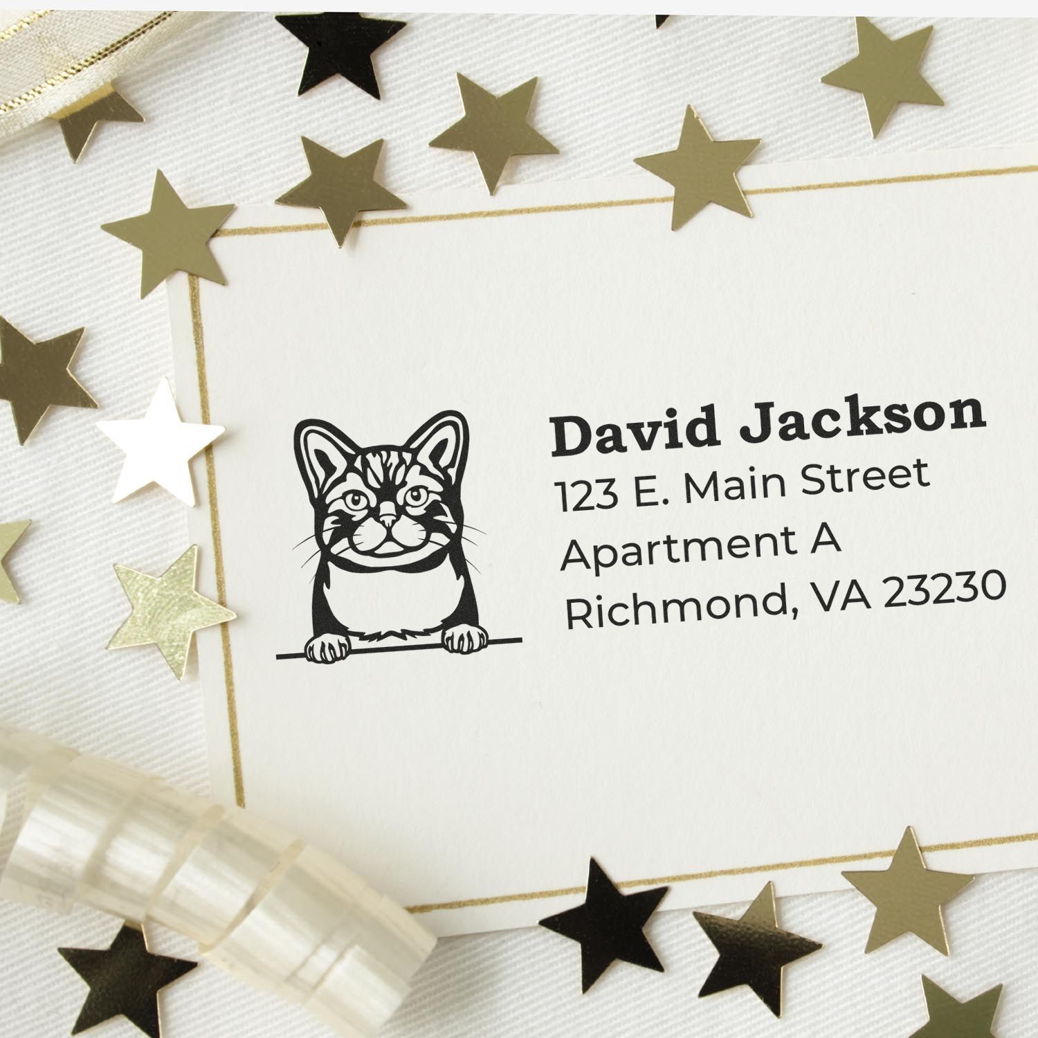 Slim Pre-Inked American Wirehair Peeking Cat Return Address Stamp on an envelope, surrounded by gold stars and ribbon, showcasing a cute cat design with address details.