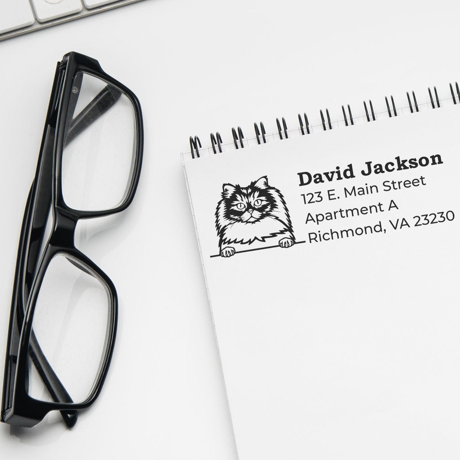 Self-Inking British Longhair Custom Address Stamp on a notepad next to glasses and a keyboard, featuring a cat illustration and sample address text.