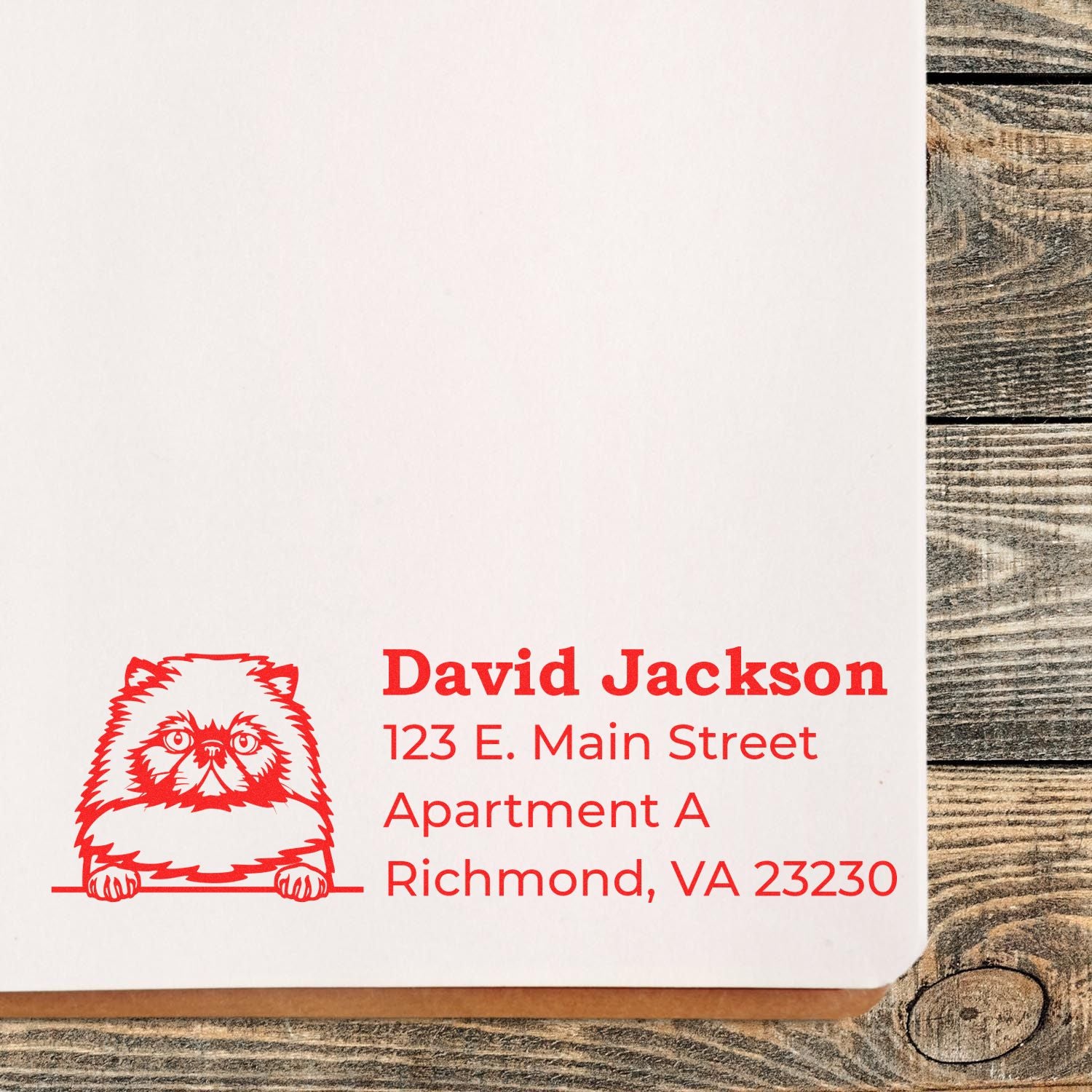 Self-Inking Himalayan Custom Address Stamp with a red cat design, featuring the name David Jackson and an address in Richmond, VA, stamped on white paper over a wooden surface.