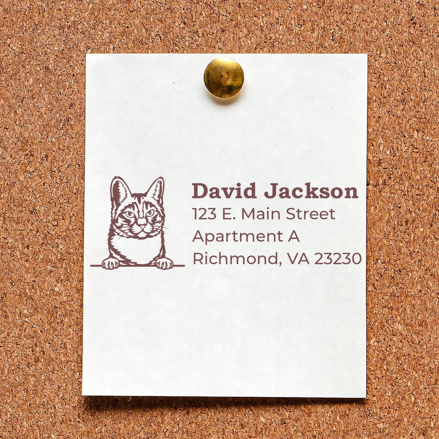 PSI Pre-Inked Peeking Manx Cat Personalized Address Stamp on a corkboard, featuring a cute cat illustration above the address details.