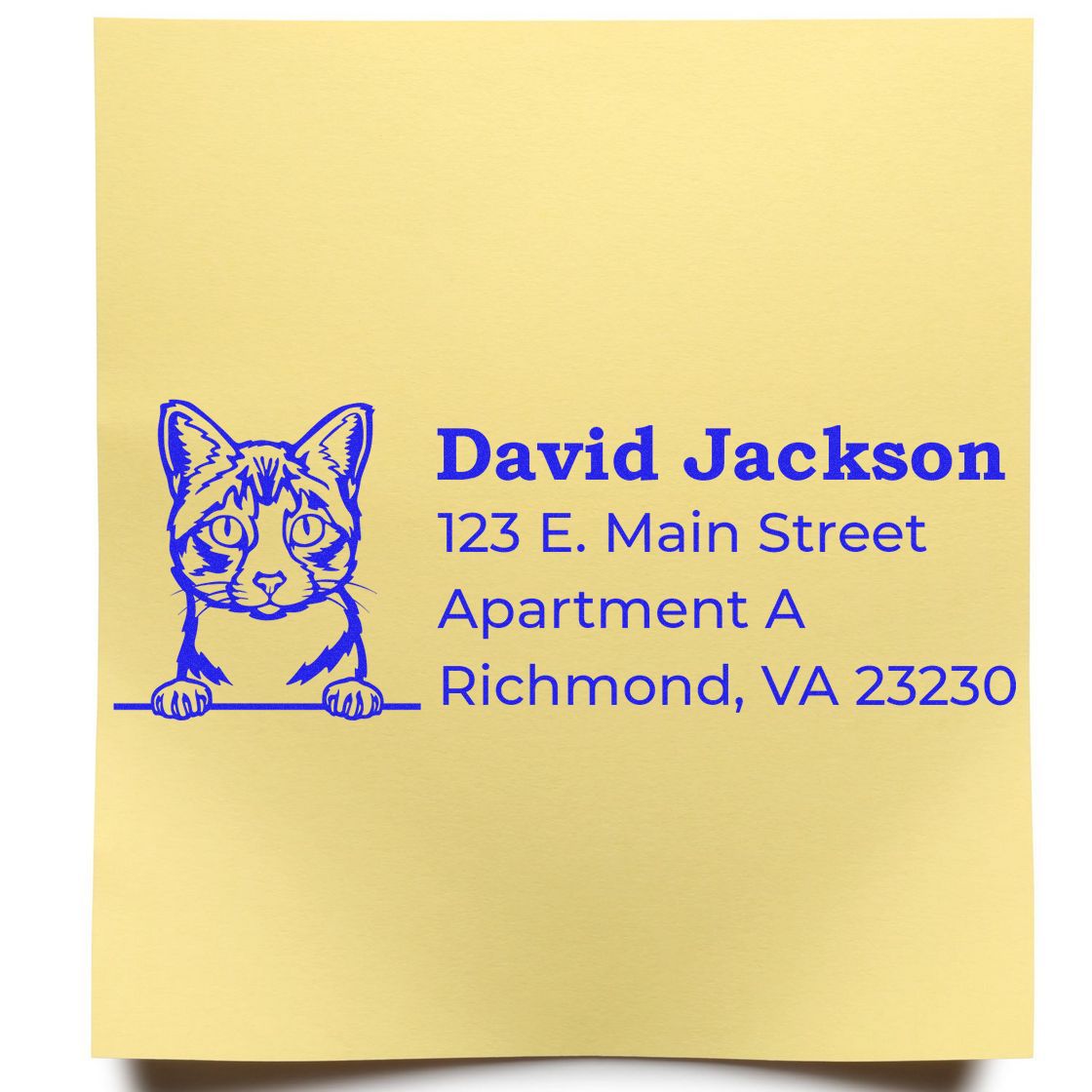 Wood Handle Ojos Azules Cat Address Stamp on yellow paper, featuring a blue cat illustration and sample address text in bold blue font.